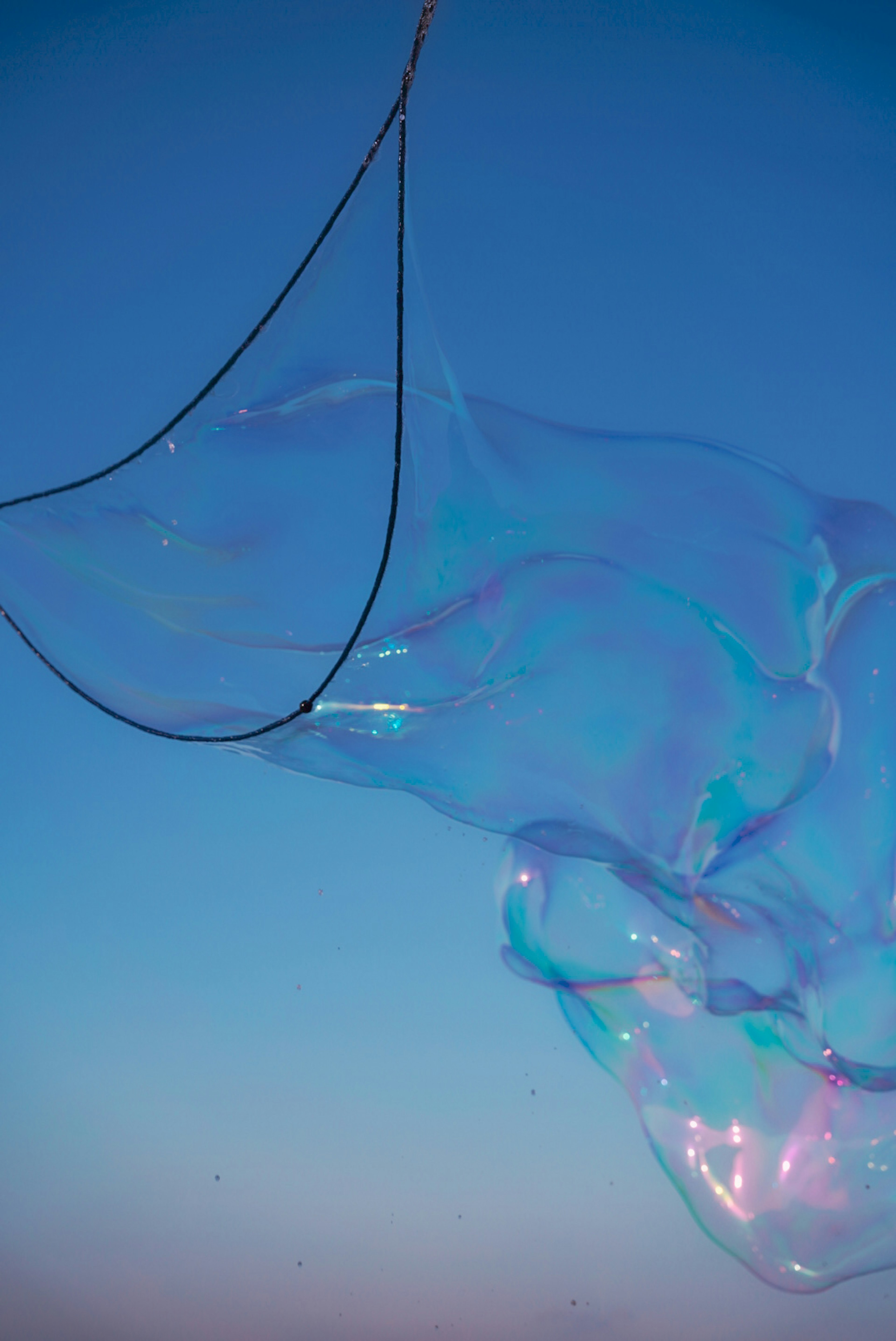 Una grande bolla di sapone che oscilla sotto un cielo blu con riflessi di luce