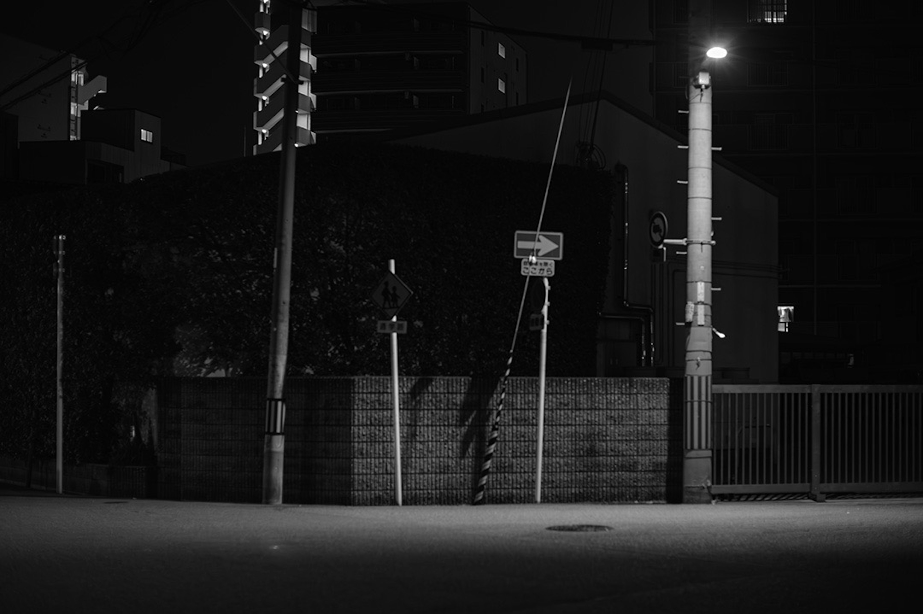 Schwarzweißfoto von einer Bushaltestelle und einer Straßenlaterne bei Nacht