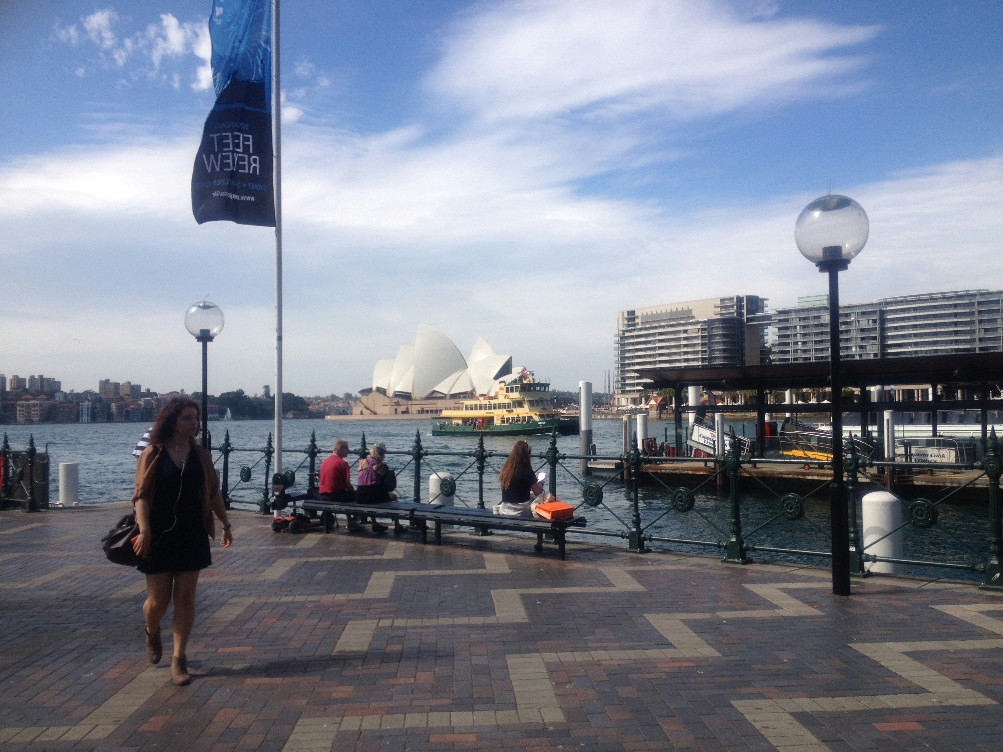 Pemandangan tepi laut dengan Sydney Opera House dan orang-orang yang berjalan