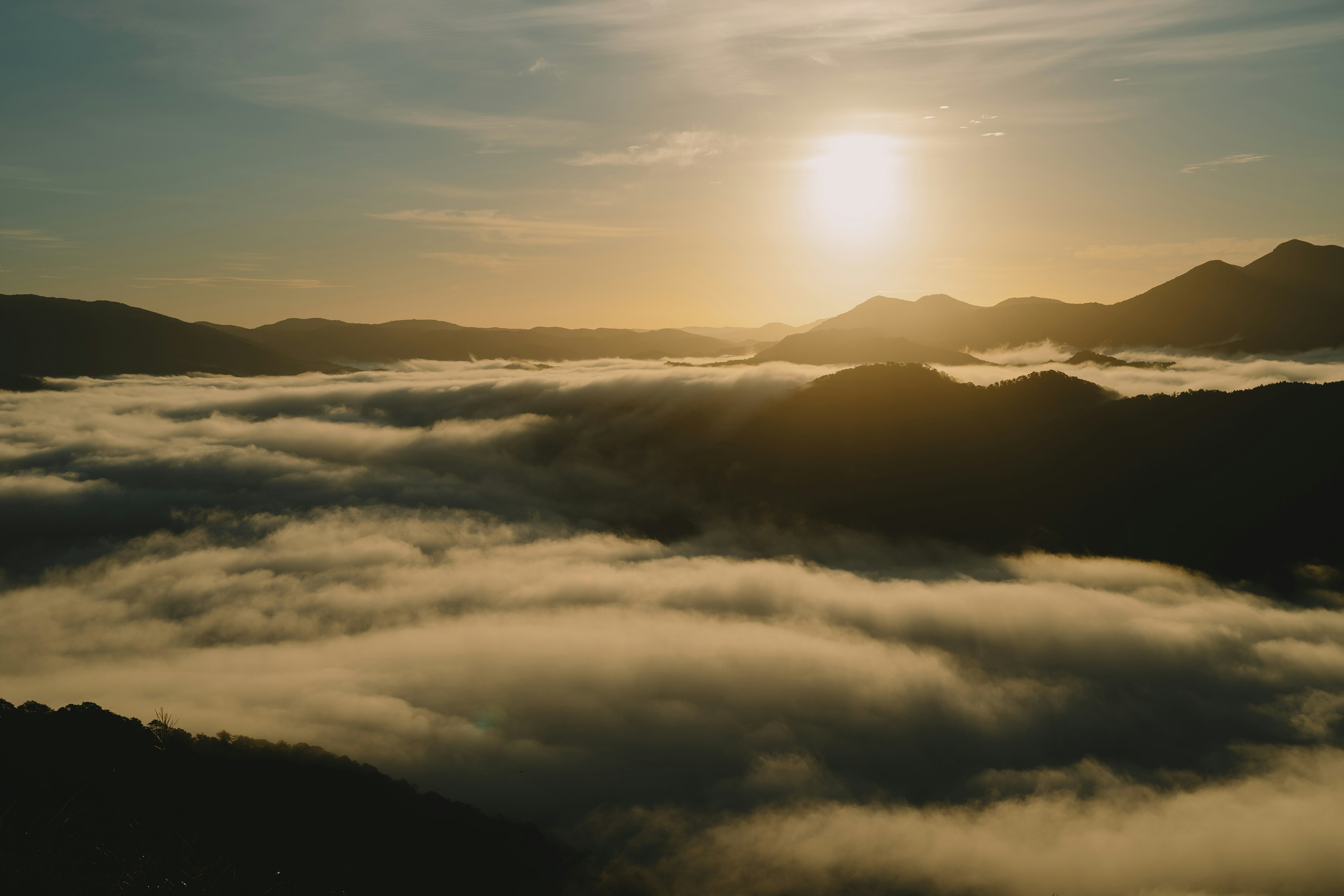 Alba che illumina un mare di nuvole sopra le montagne