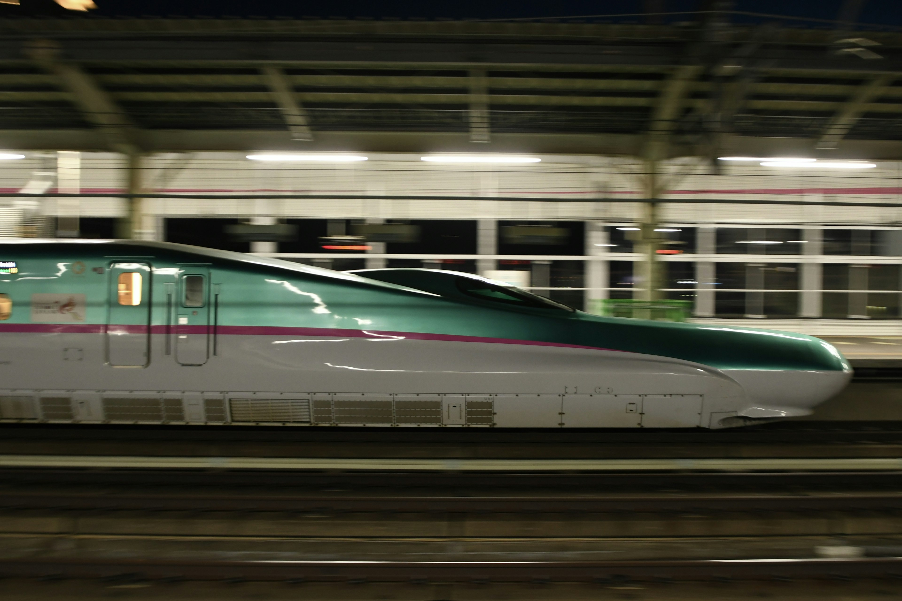 Shinkansen, der nachts durch einen Bahnhof fährt