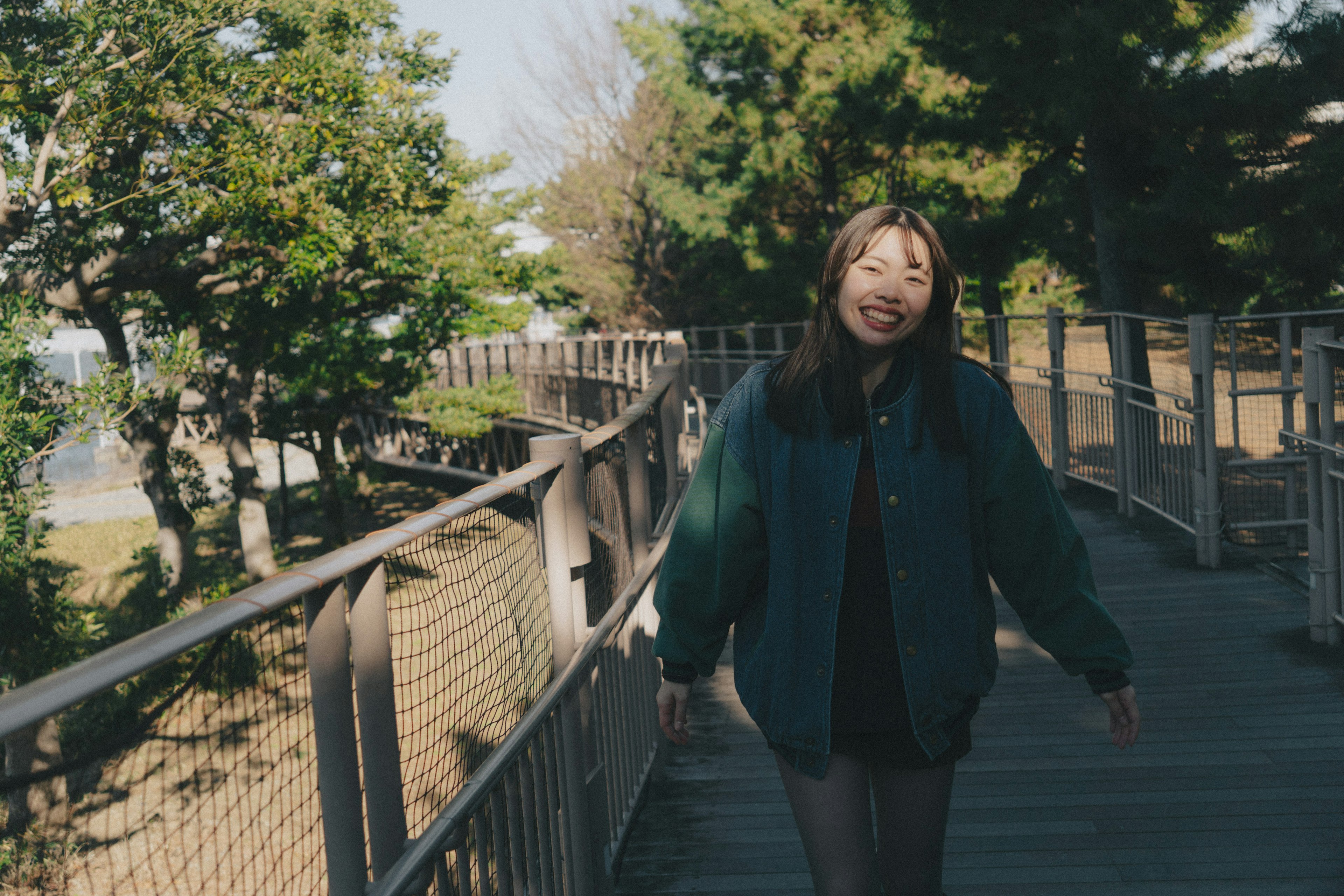 Woman walking on a wooden path in a park smiling happily