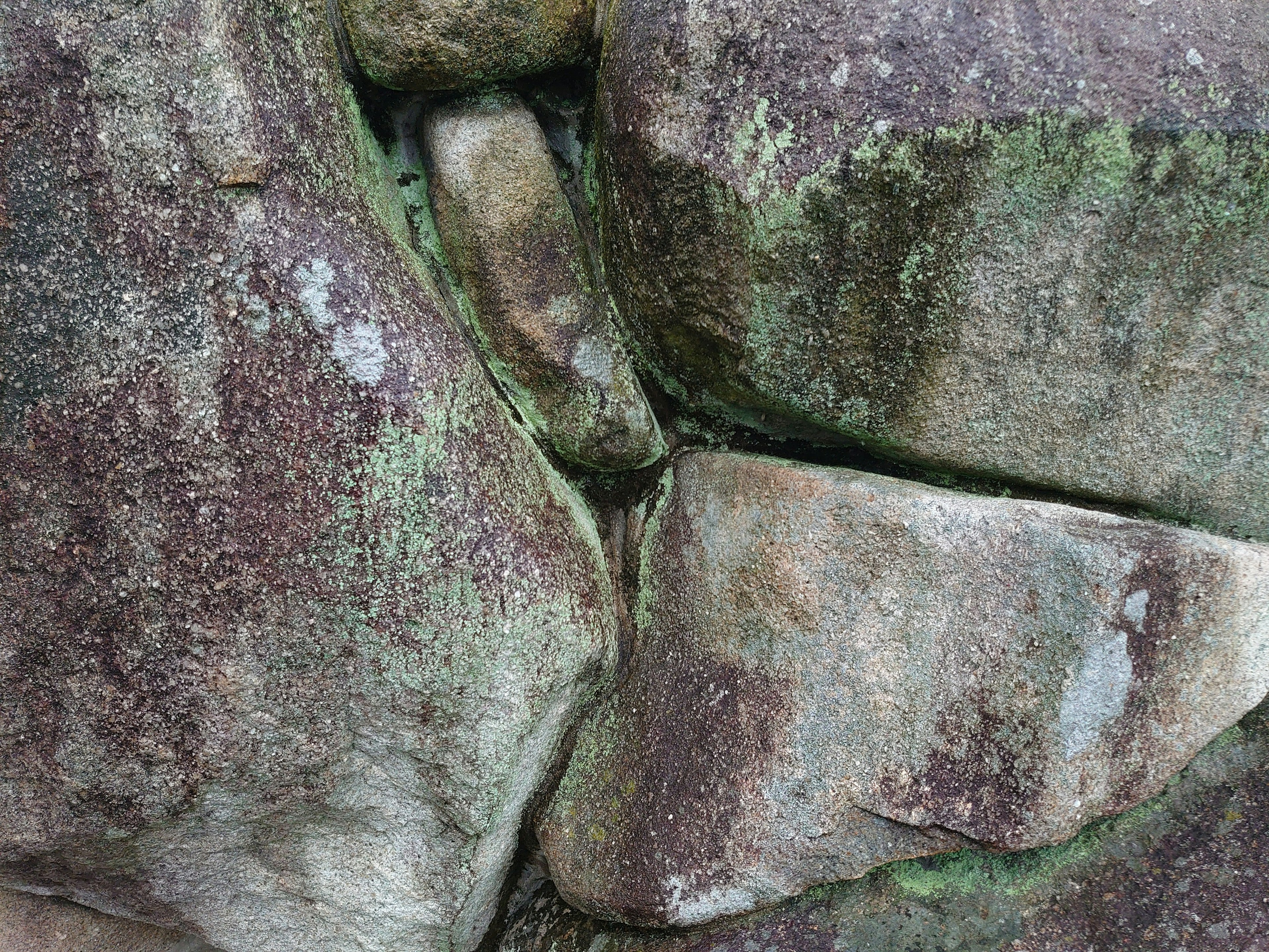 古代の石の構造物の一部で、苔が生えた岩の接合部が見える