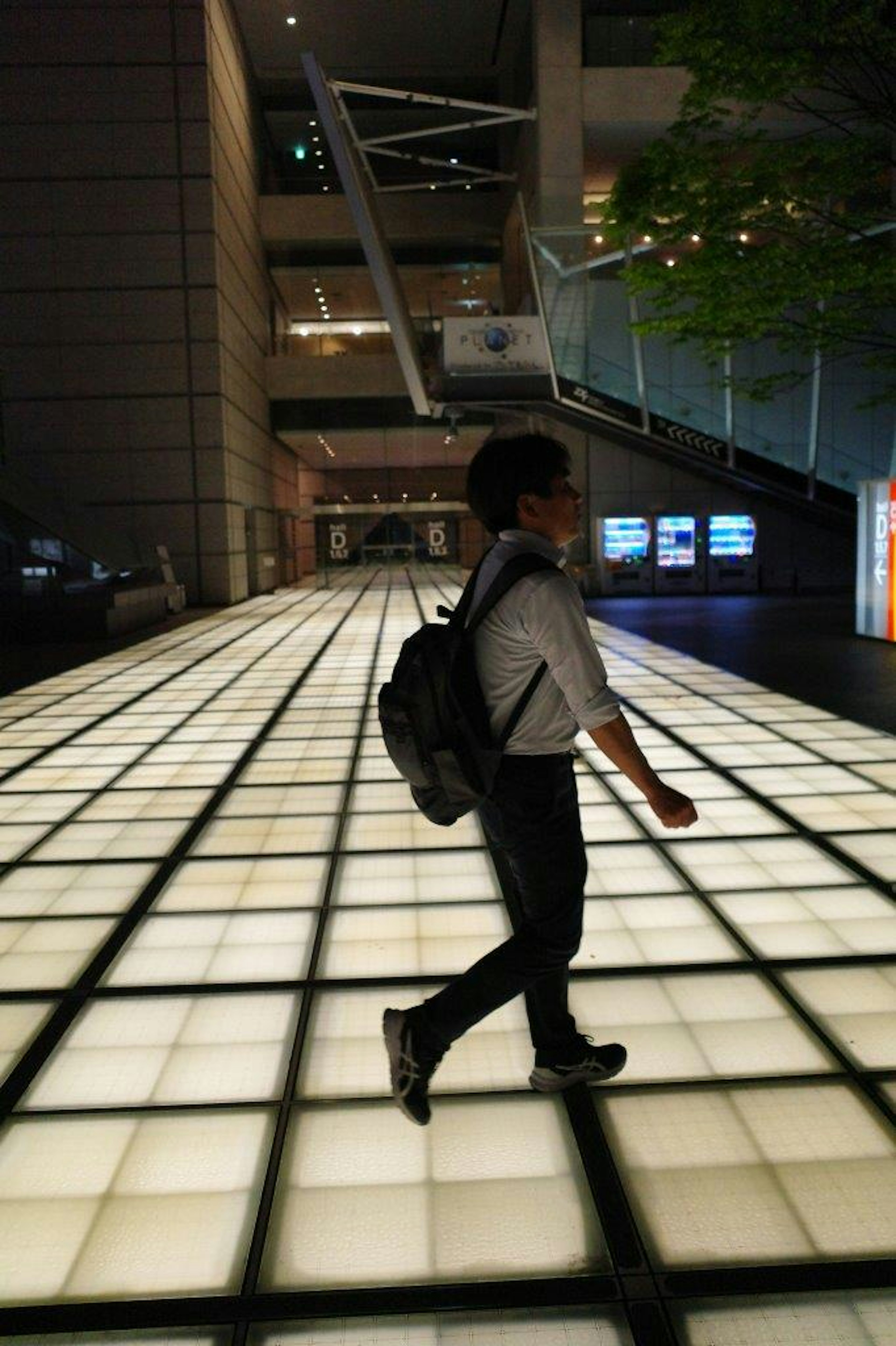 Un giovane che cammina su un pavimento illuminato