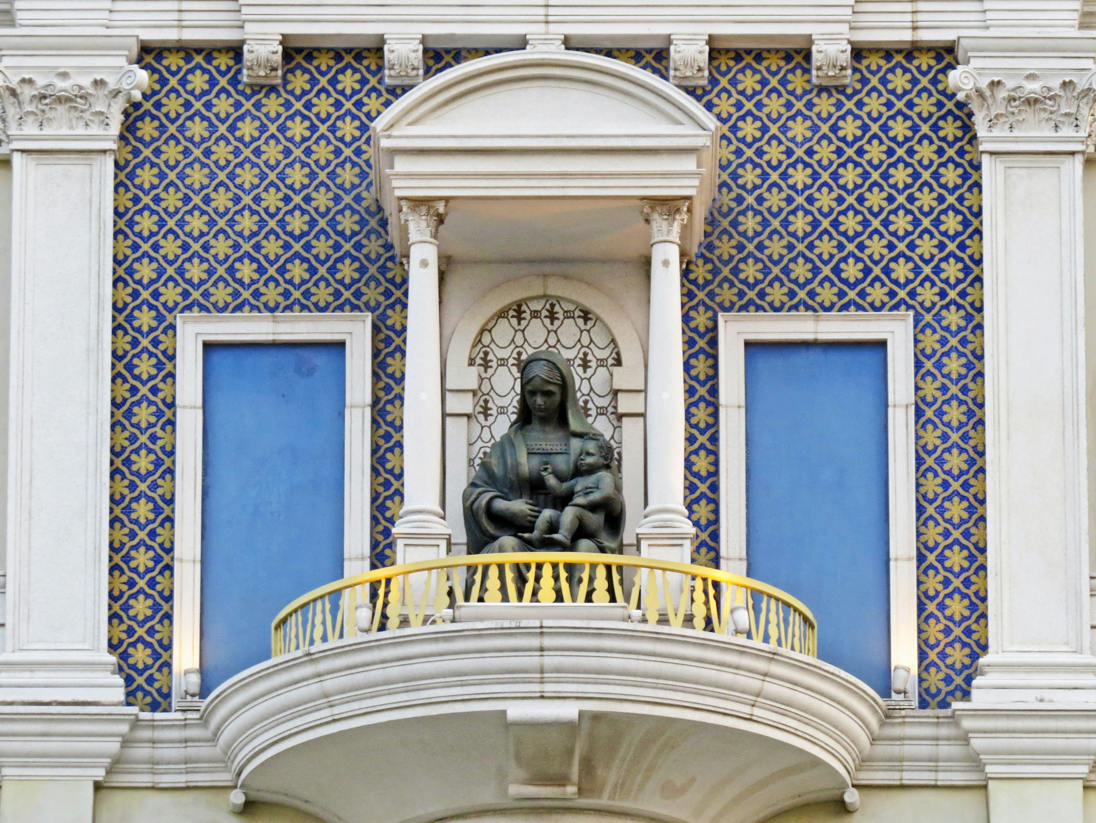 Statue of Mary with child on a balcony surrounded by decorative tiles