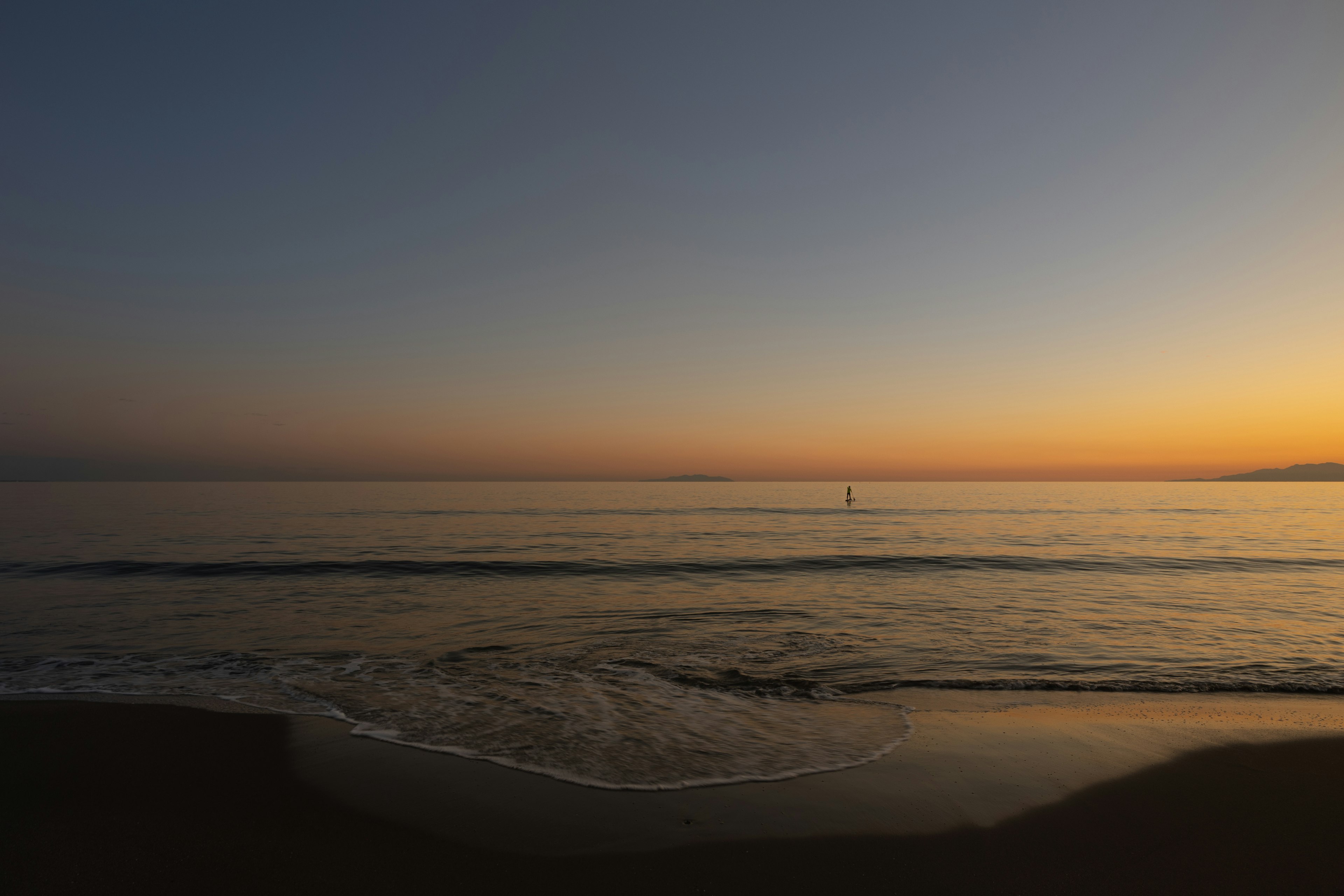 Tramonto sull'oceano con onde tranquille e cielo arancione