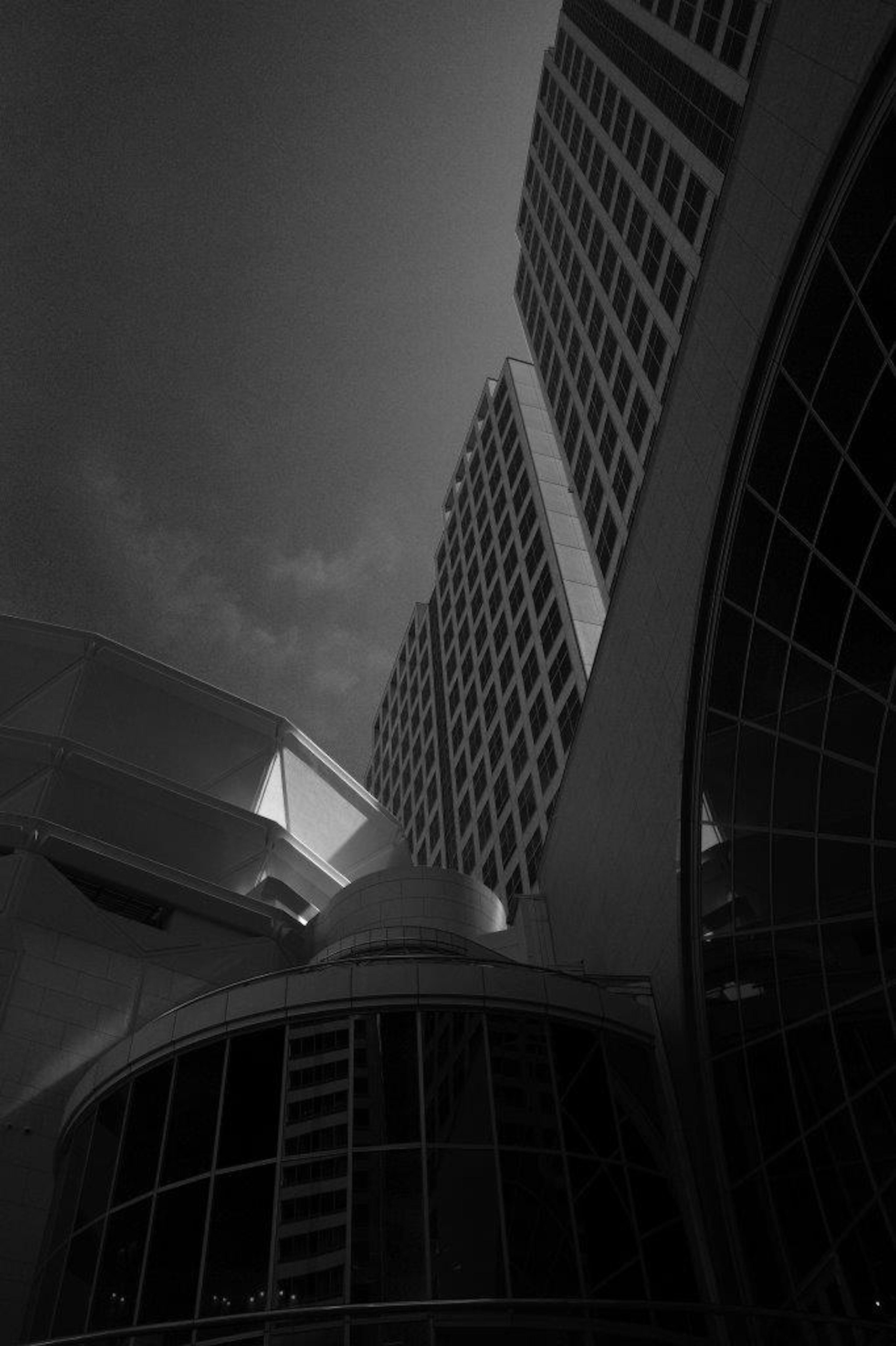 Black and white image of tall buildings from an angled perspective Contrasting curves and straight lines of architecture