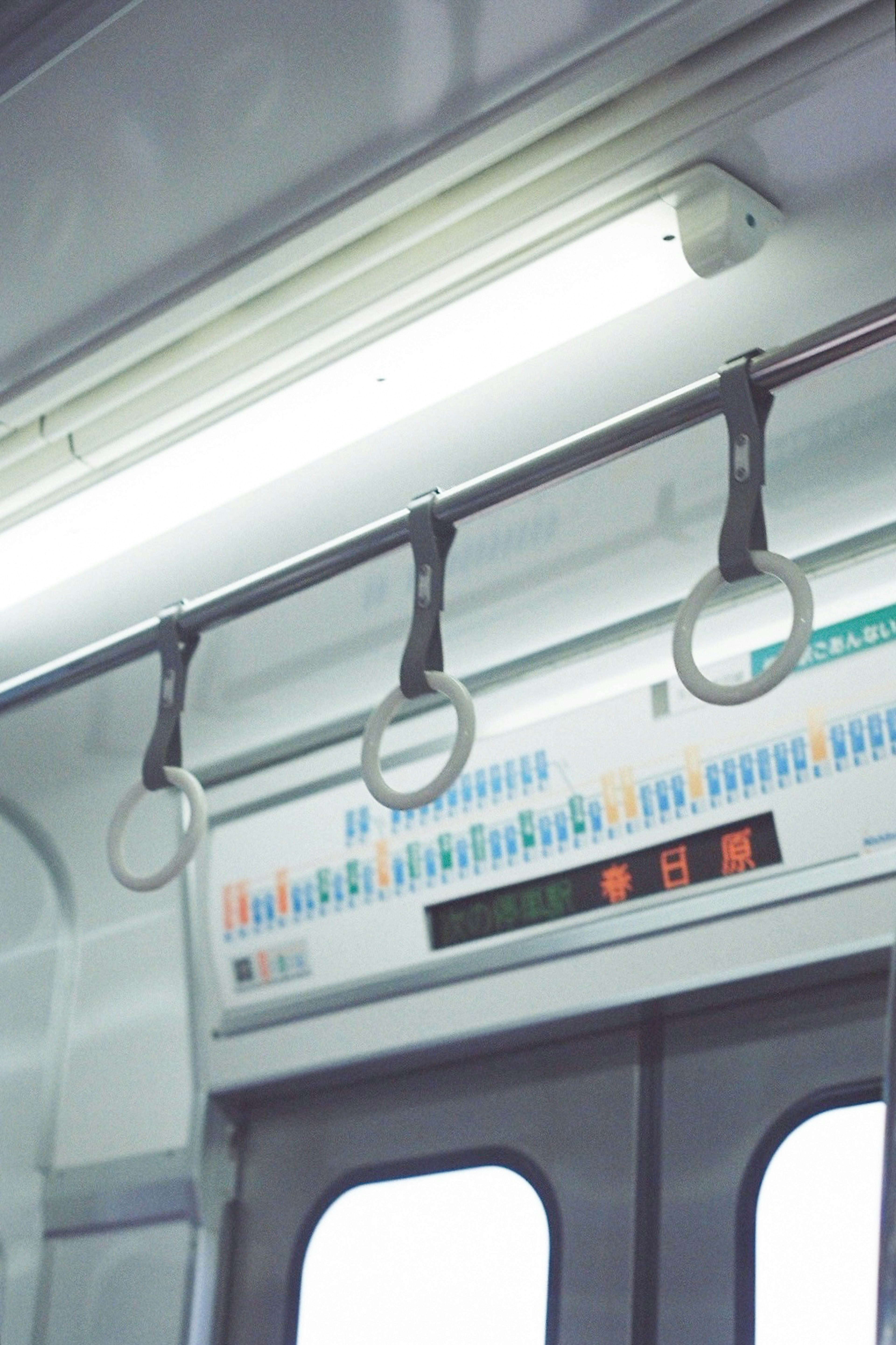 Interior of a train featuring grab handles and a display of train schedule