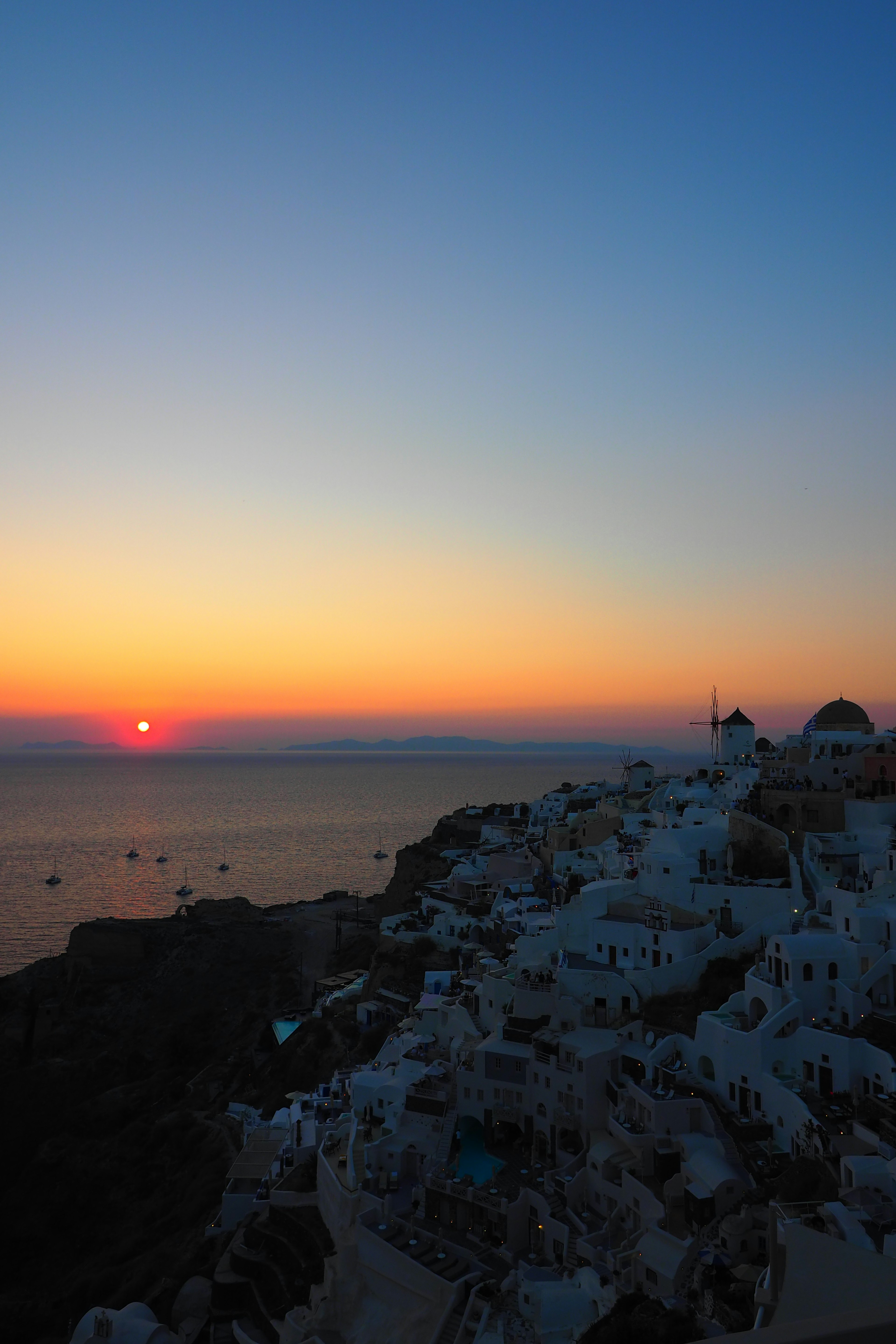 Stunning sunset over the sea in Santorini with white buildings