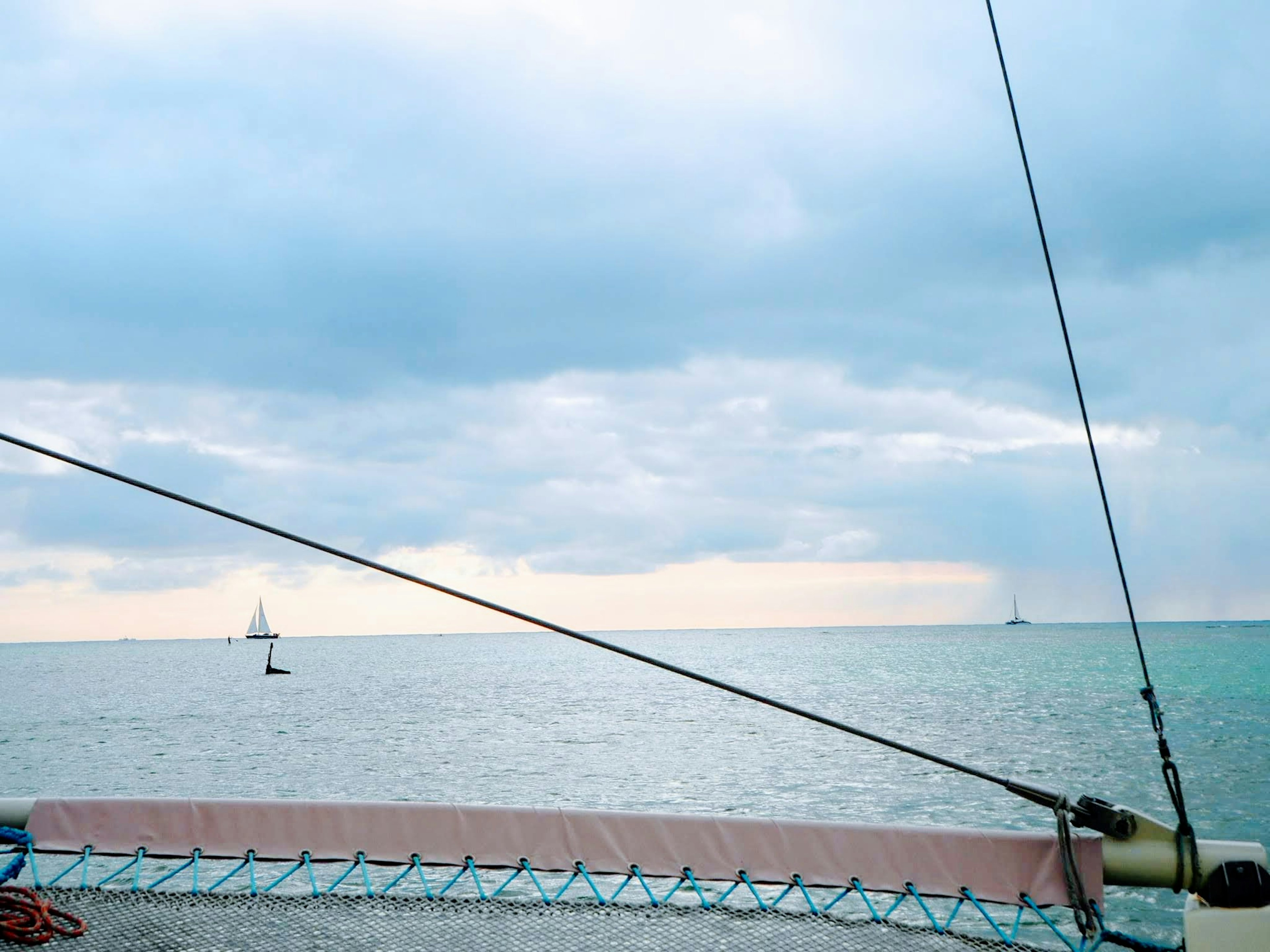 Meereslandschaft mit einem Yacht, die am Horizont unter bewölktem Himmel segelt