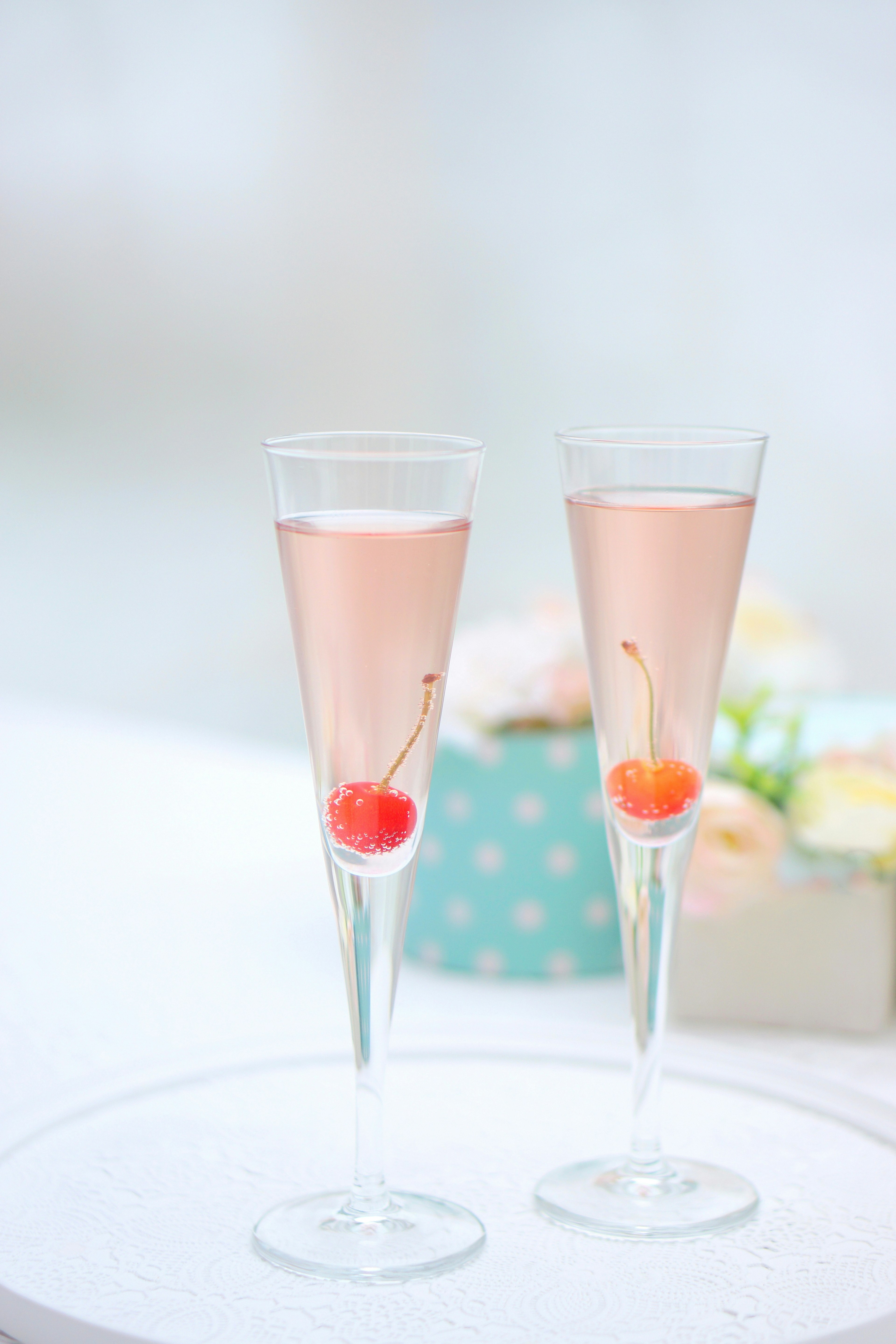 Two champagne glasses with pink drink and cherries inside