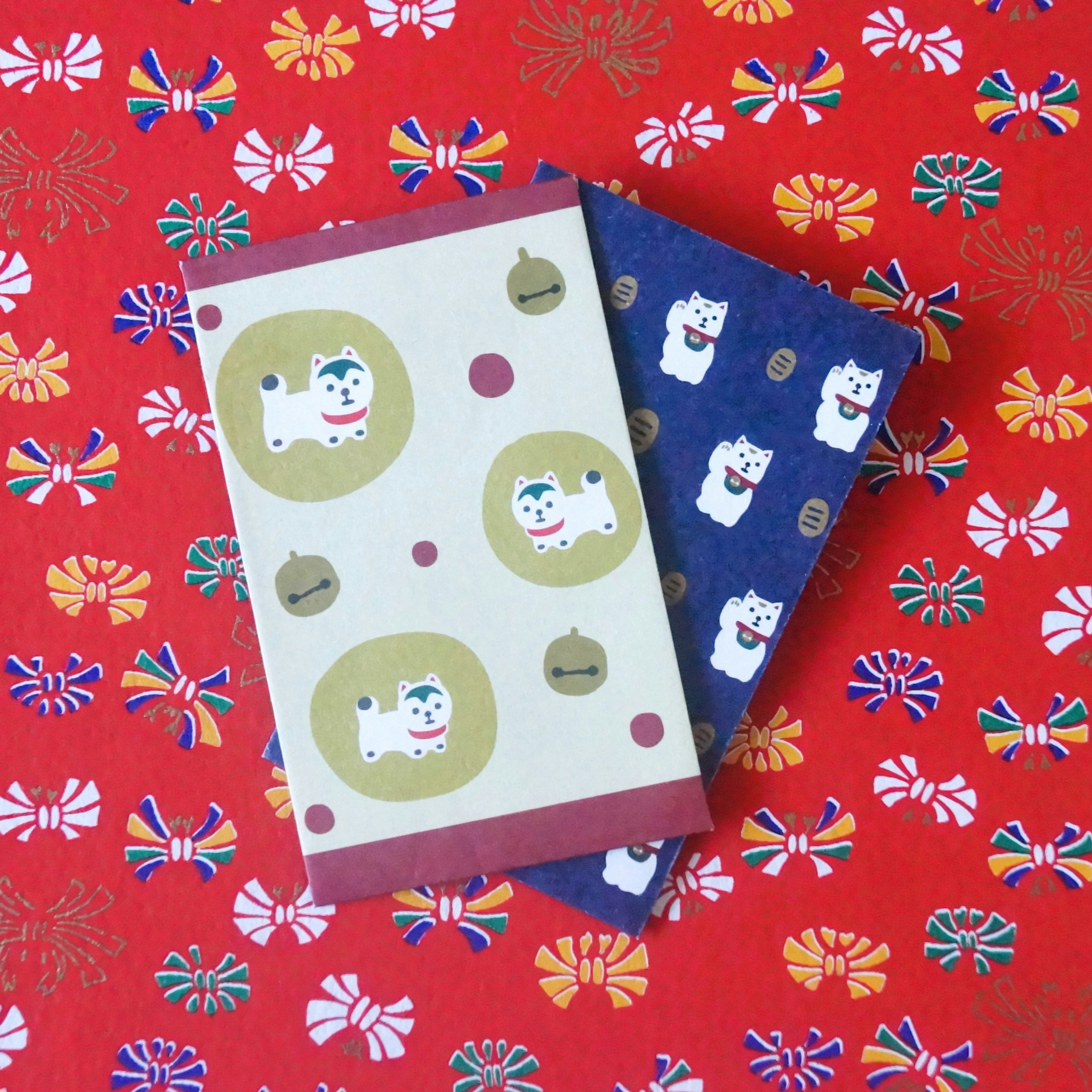 Two notebooks with dog illustrations on a red floral background