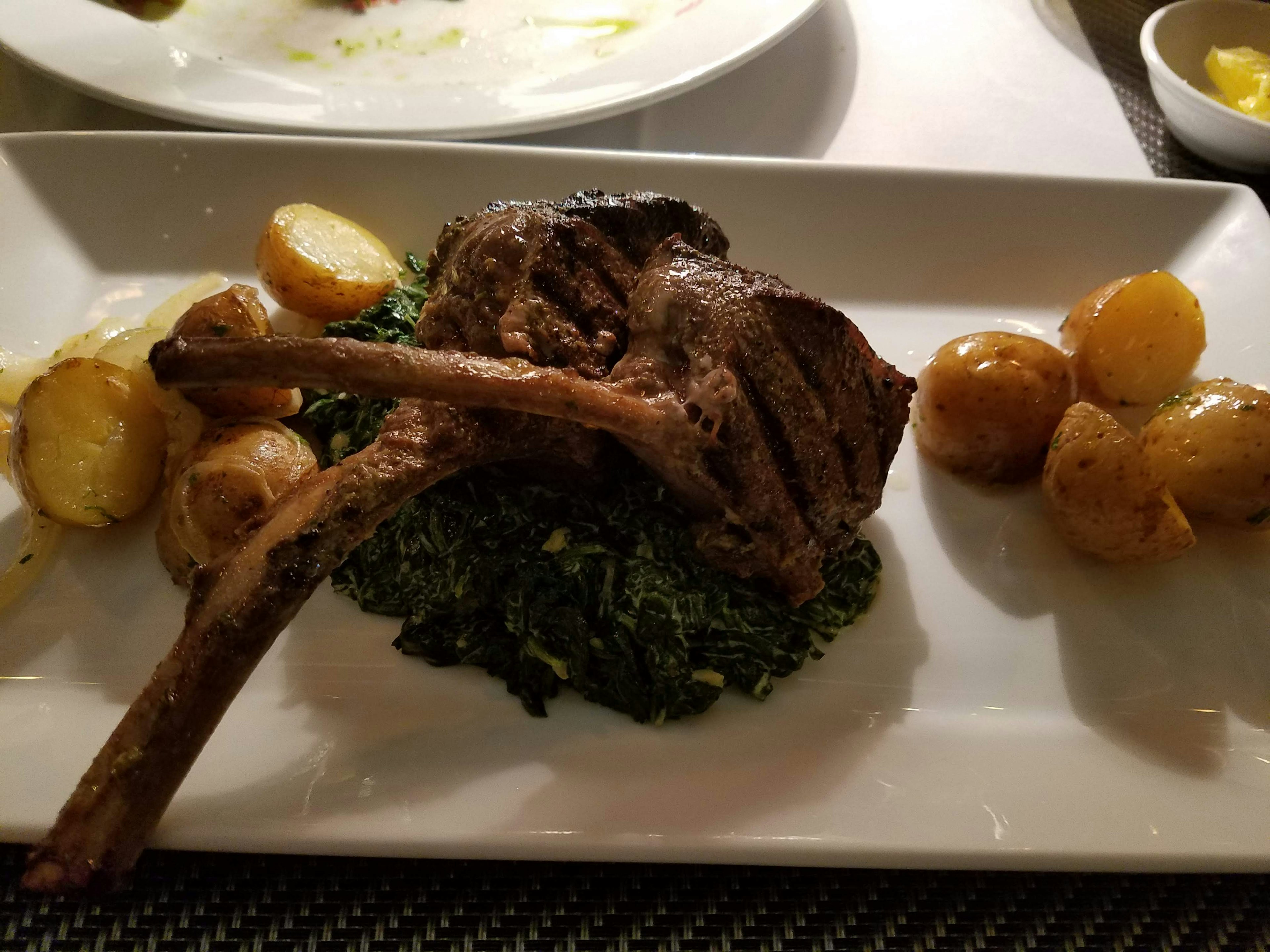 Succulent lamb chop served over creamy kale with roasted potatoes