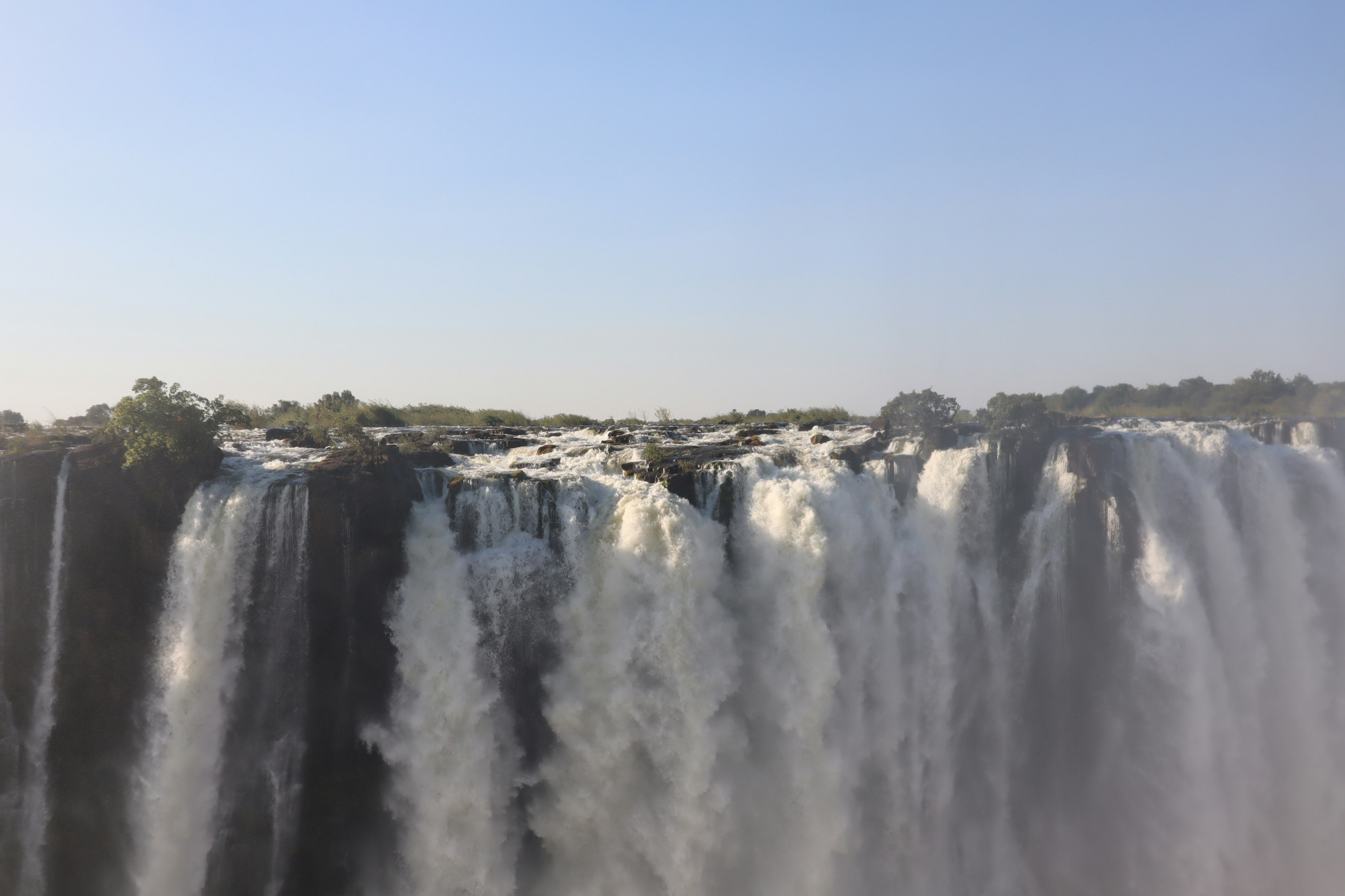 Majestätischer Wasserfall, der unter einem blauen Himmel fließt