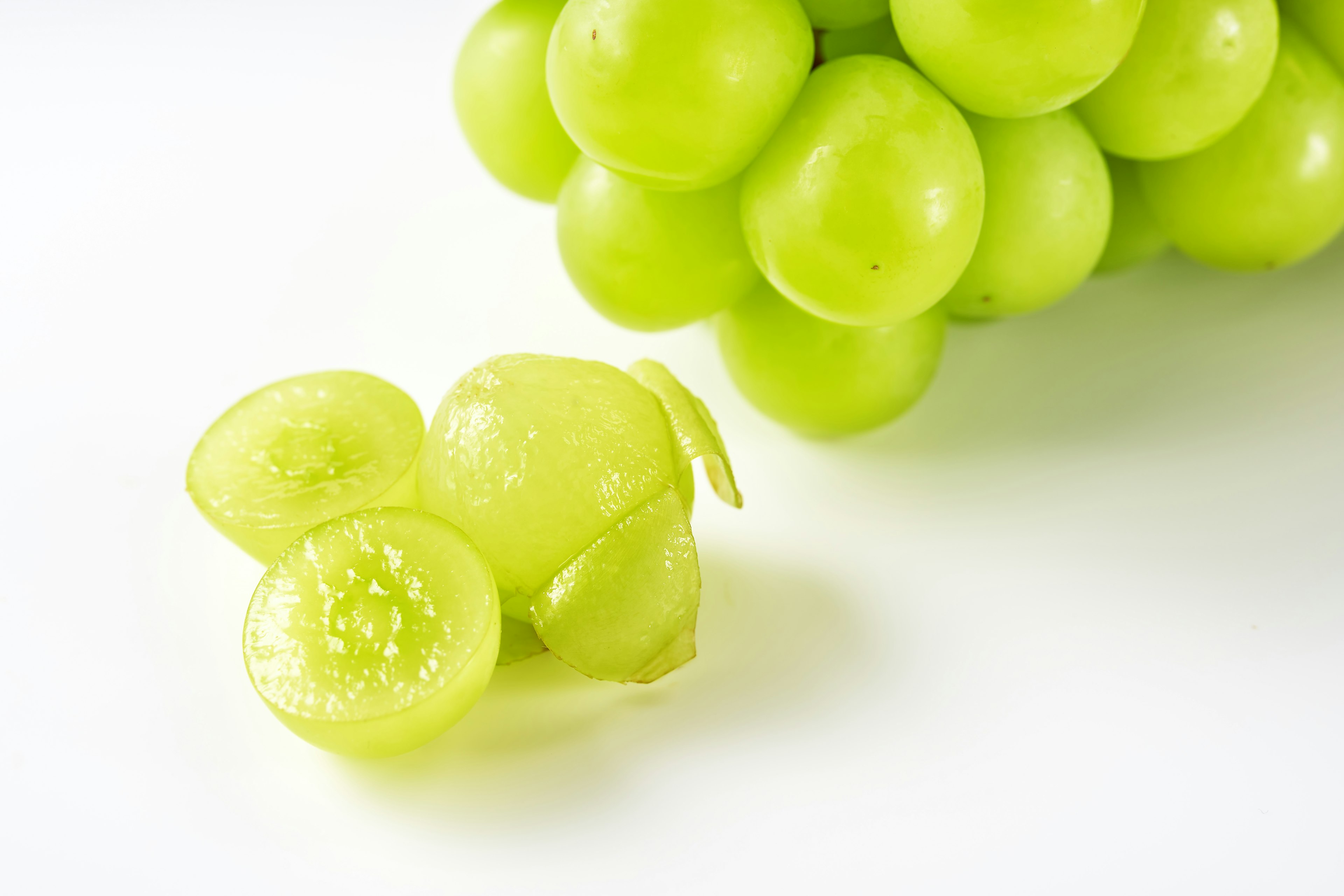 A cluster of vibrant green grapes with a sliced grape