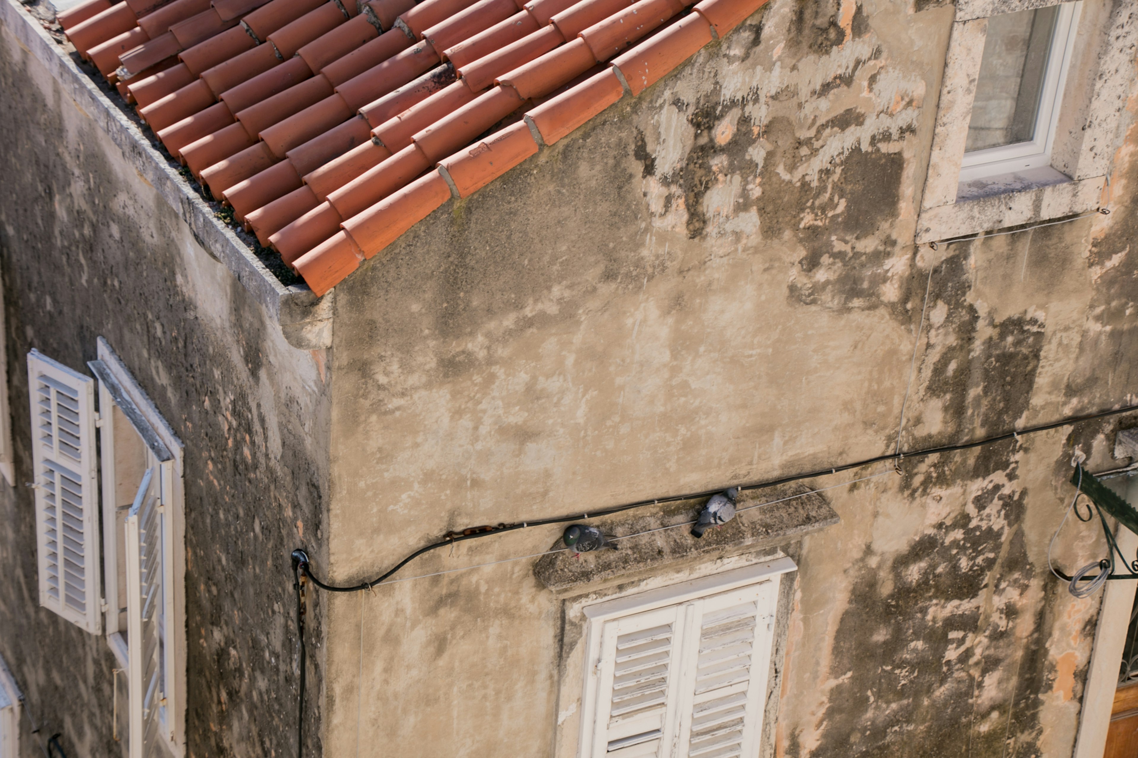 Corner of an old building with textured wall and red tiled roof