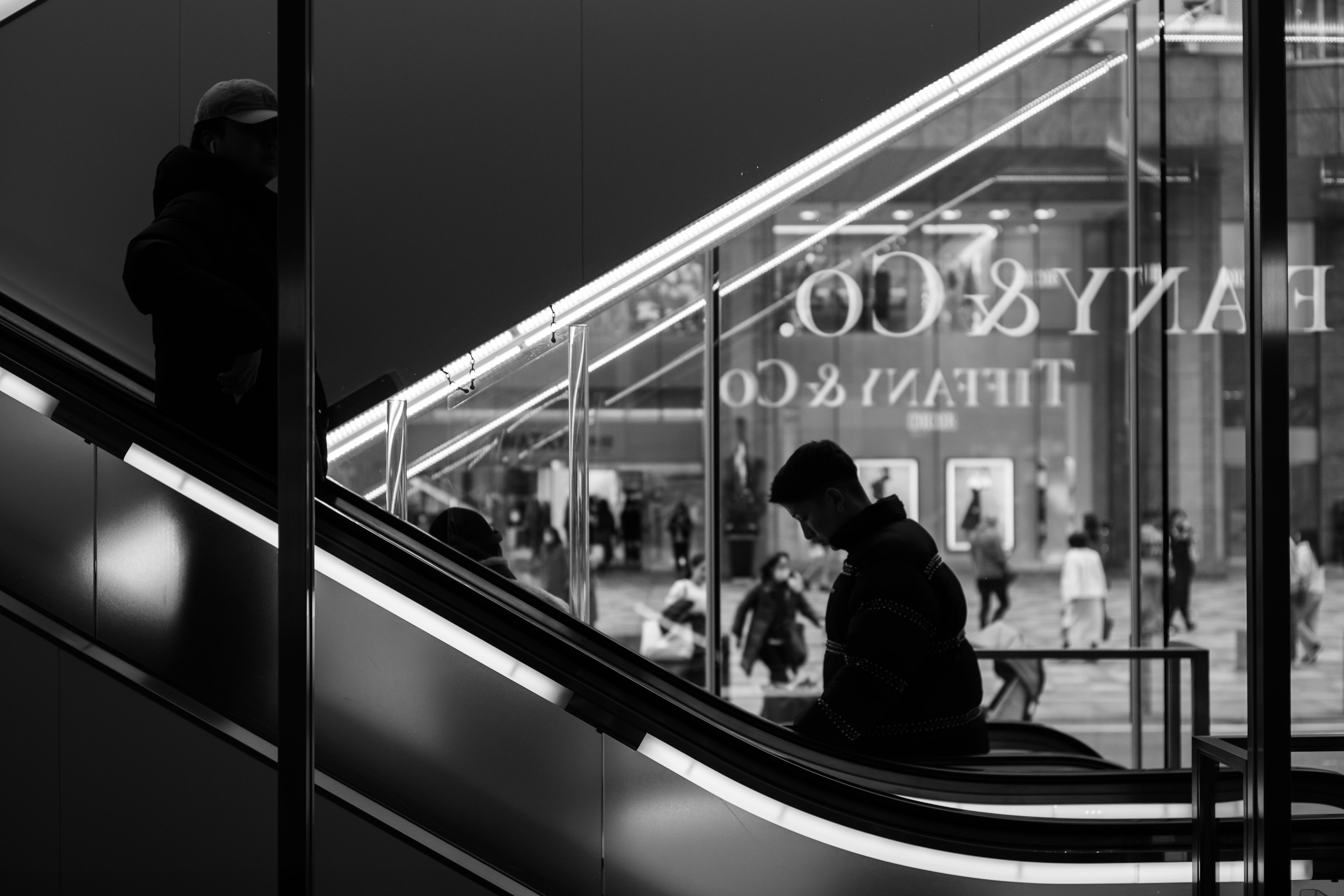 Silhouette of a person on an escalator with a shopping area in the background