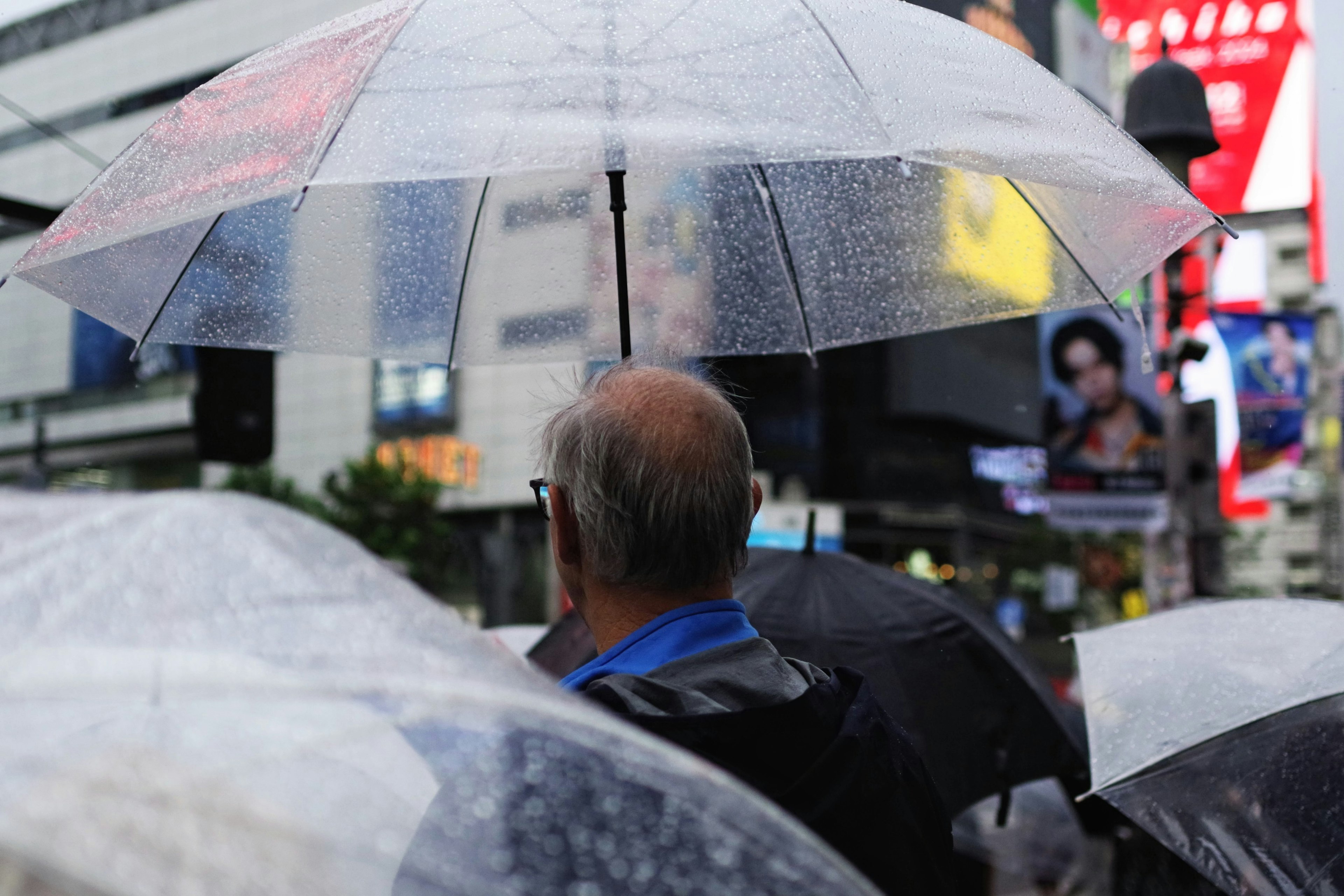 ชายคนหนึ่งถือร่มในฝนพร้อมร่มอื่นๆรอบตัวเขา