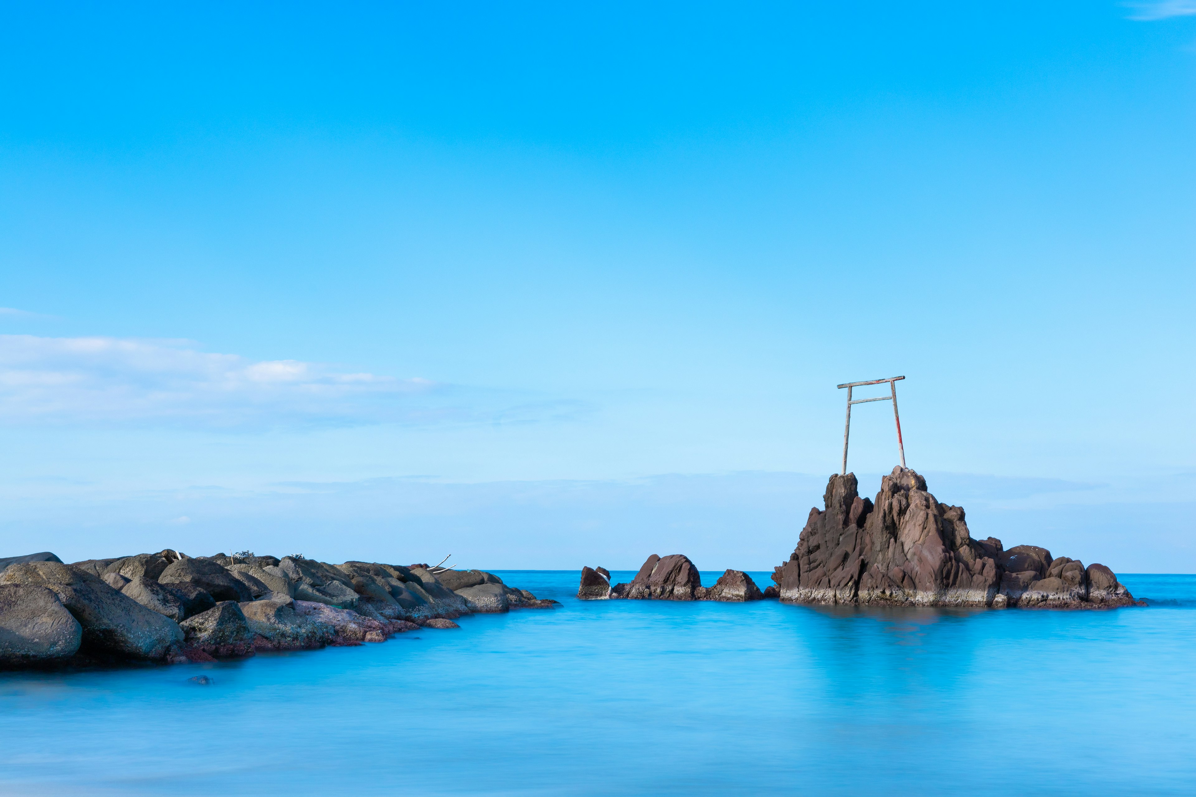 Torii di atas batu di bawah langit dan laut biru