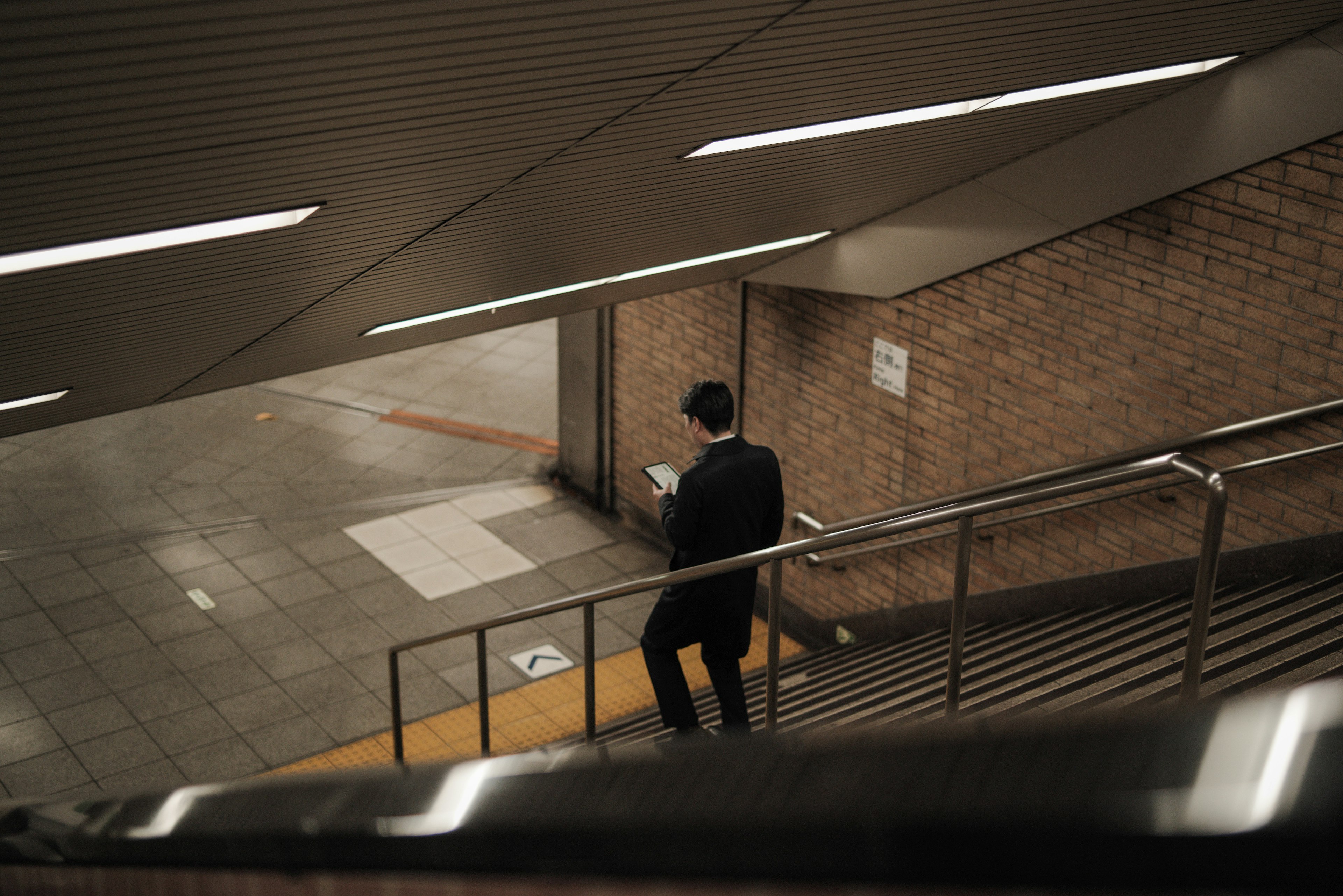 Uomo che scende le scale della metropolitana con illuminazione moderna