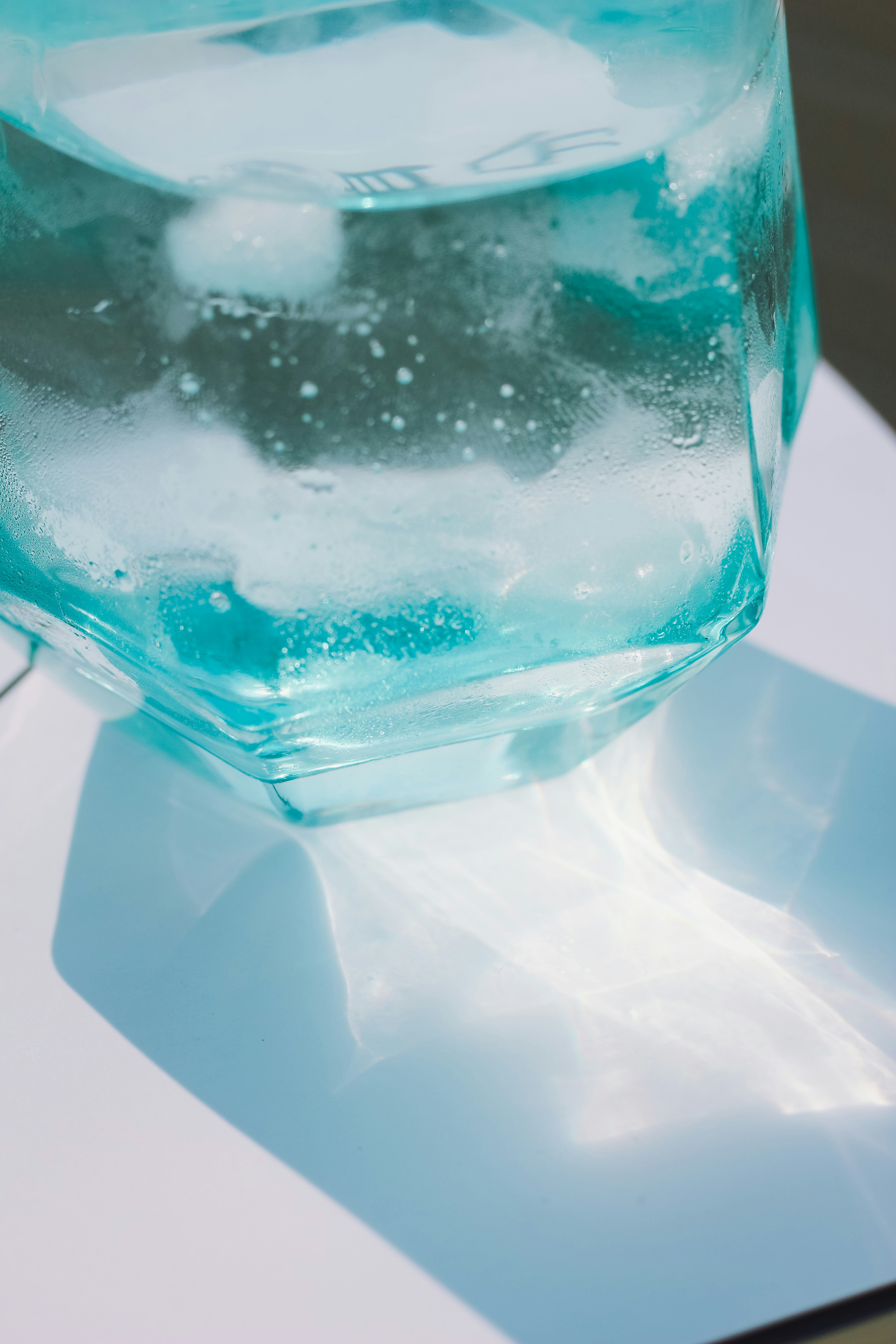 Blue glass container filled with water casting a shadow