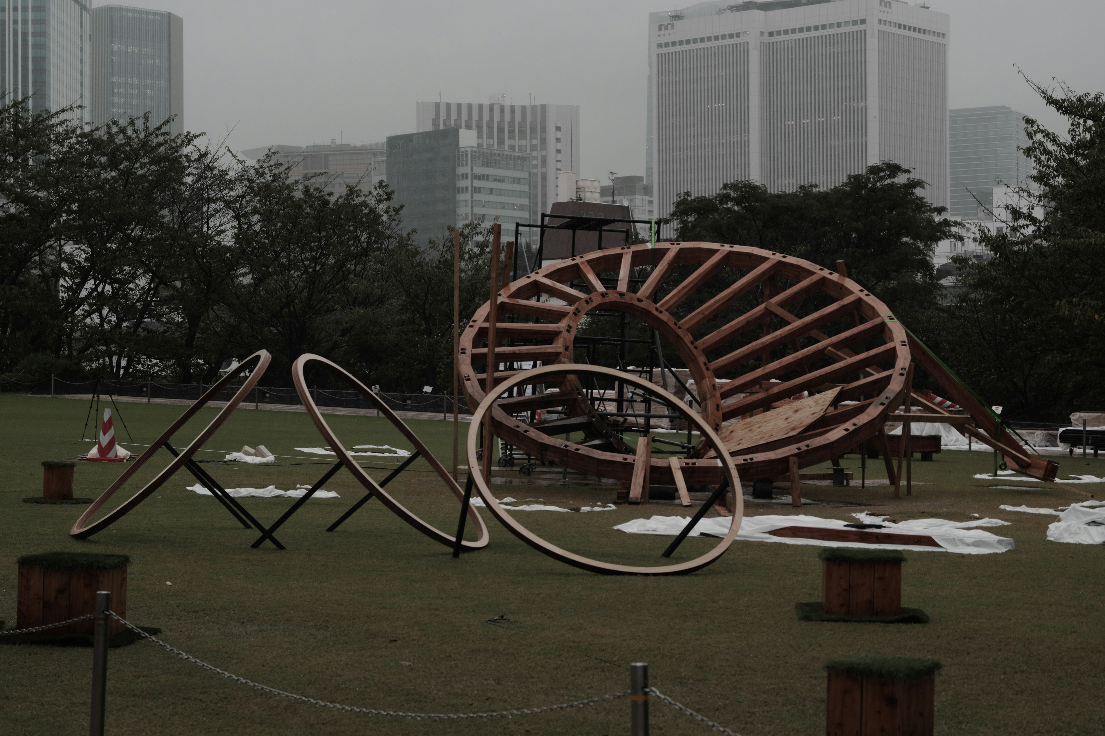 Instalación artística de madera en un parque con el horizonte de la ciudad de fondo