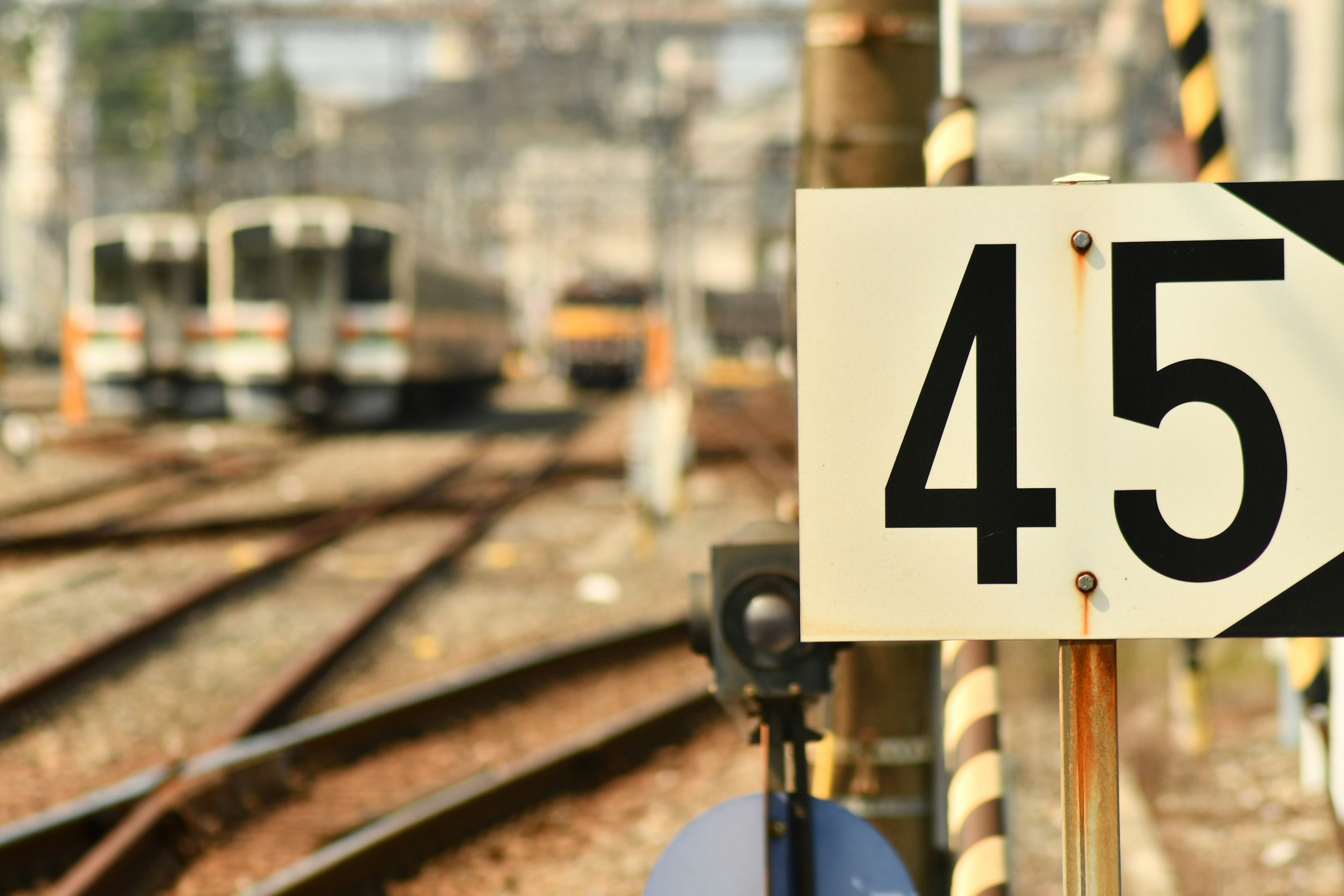 Railway signal board number 45 with trains in the background