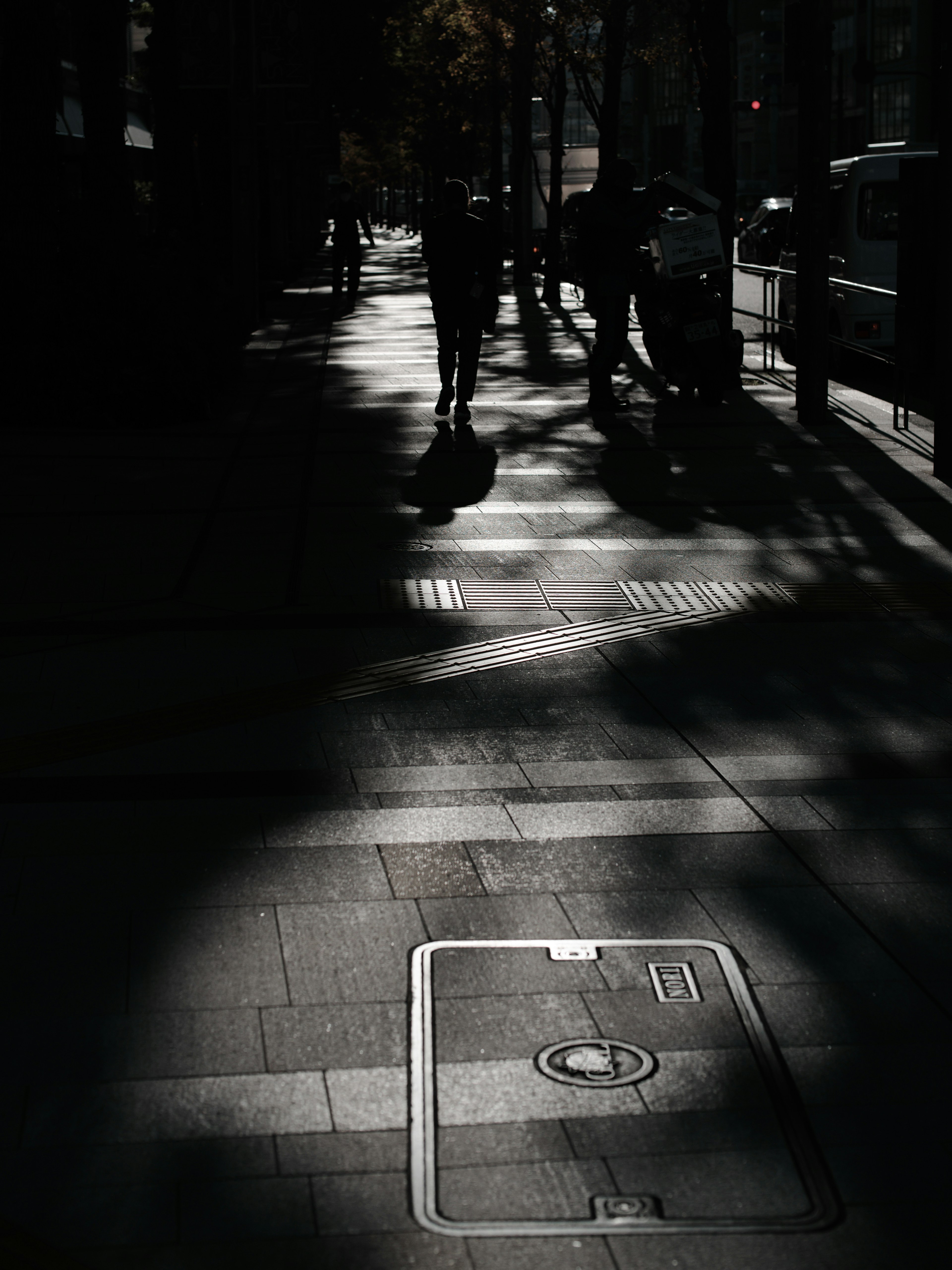 Calle débilmente iluminada con sombras y siluetas de personas