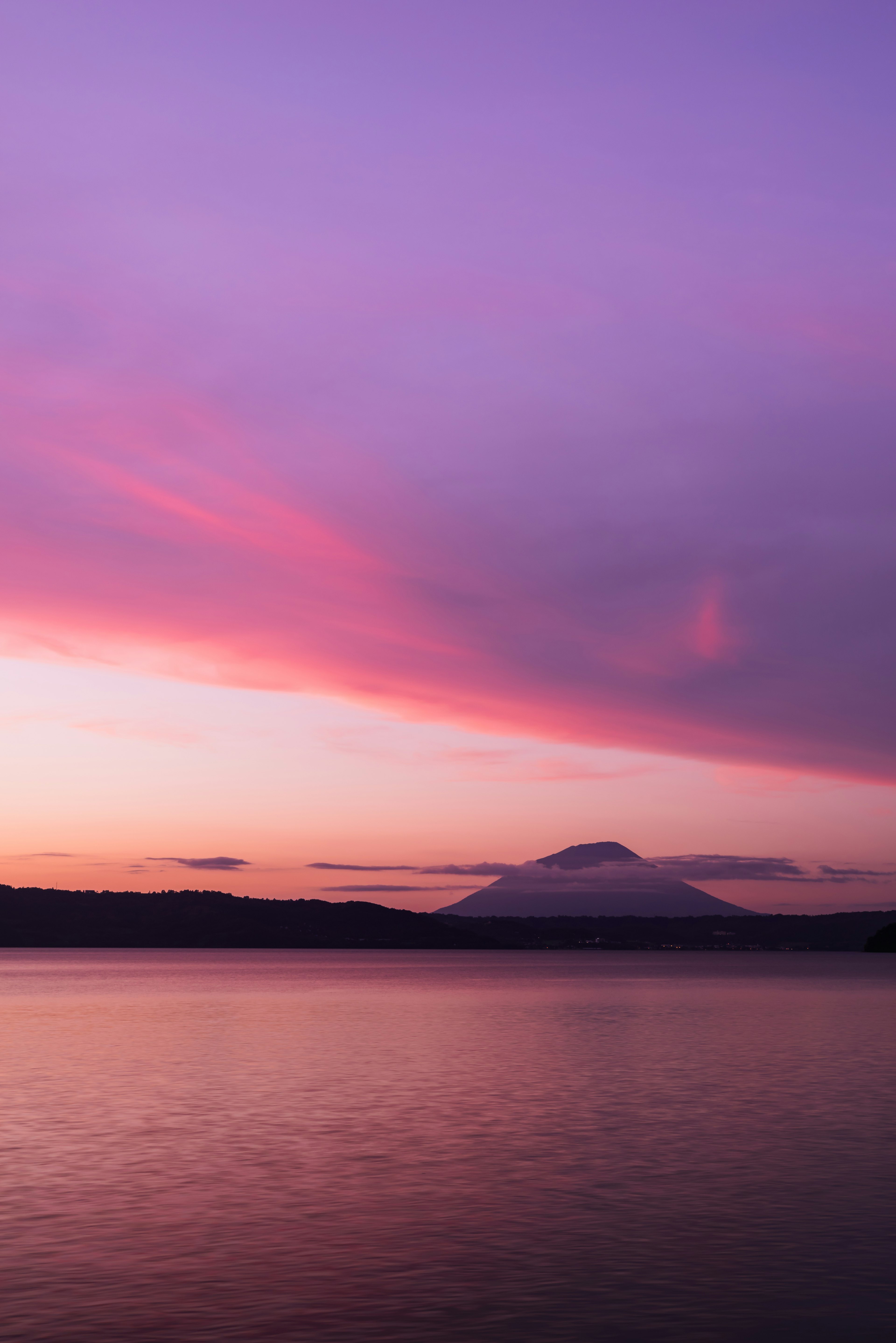 美しい紫色の空と山のシルエットを映す静かな湖の風景