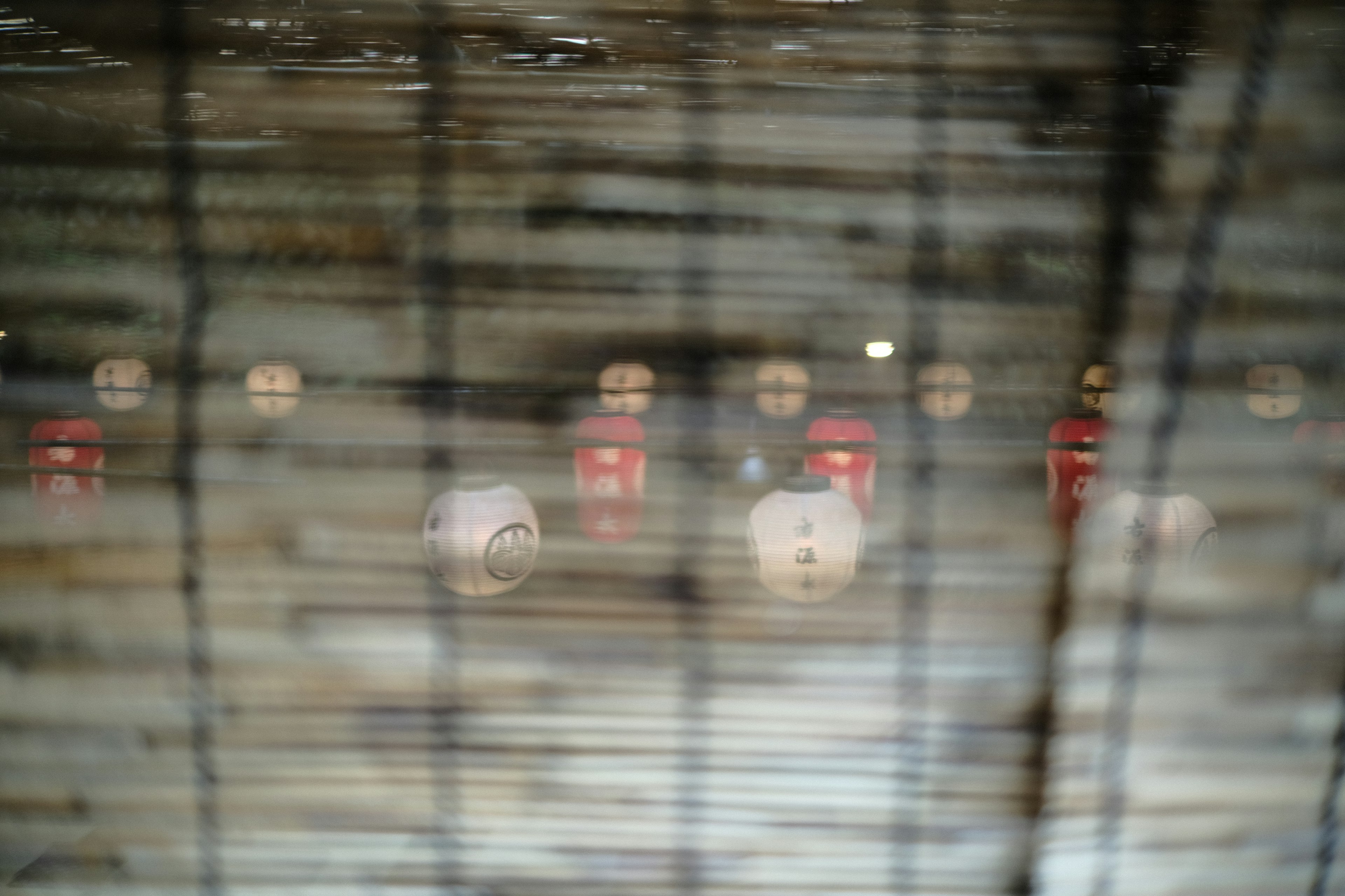 A view of red and white spherical decorations seen through a mesh