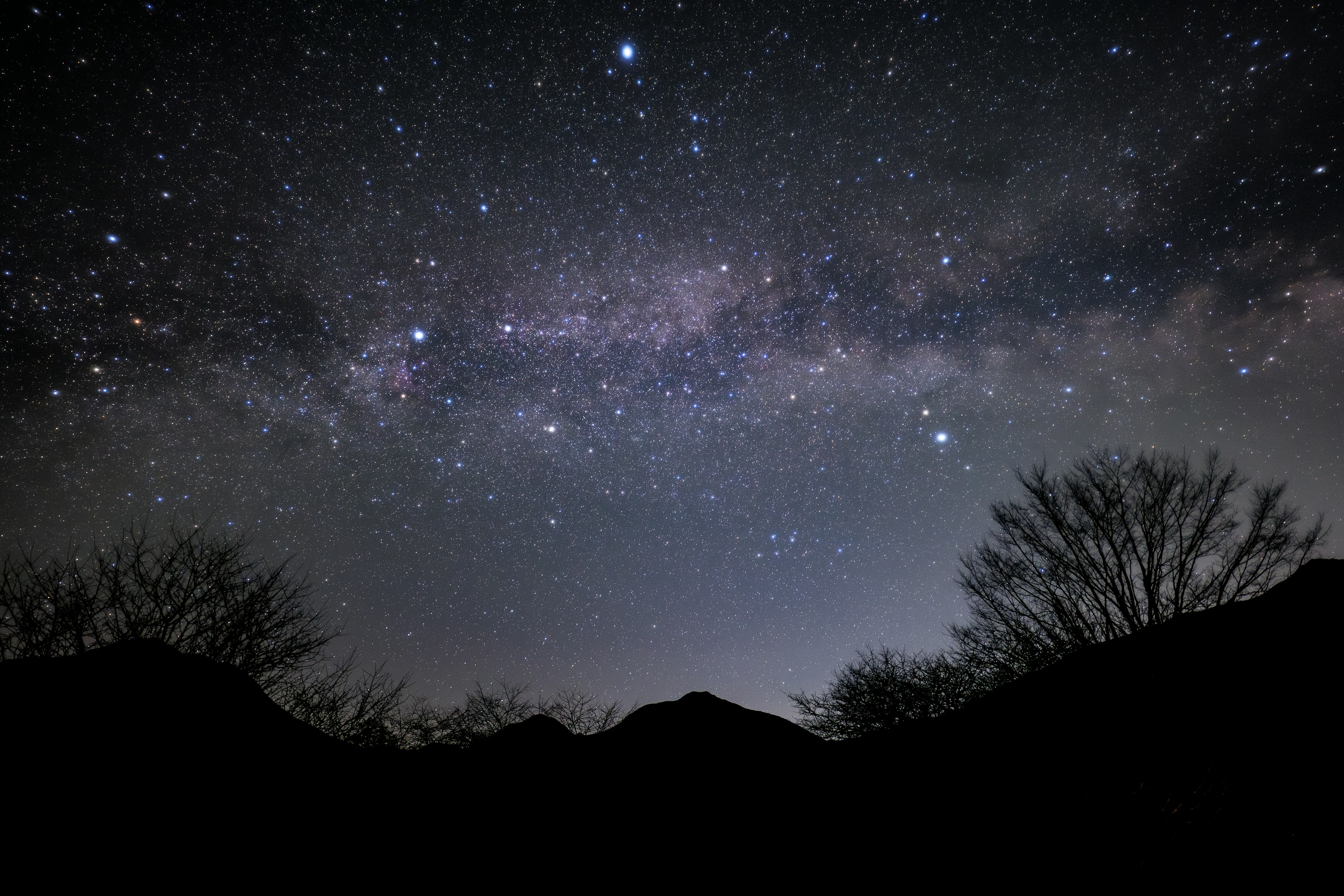 星空に広がる銀河の帯とシルエットの山々