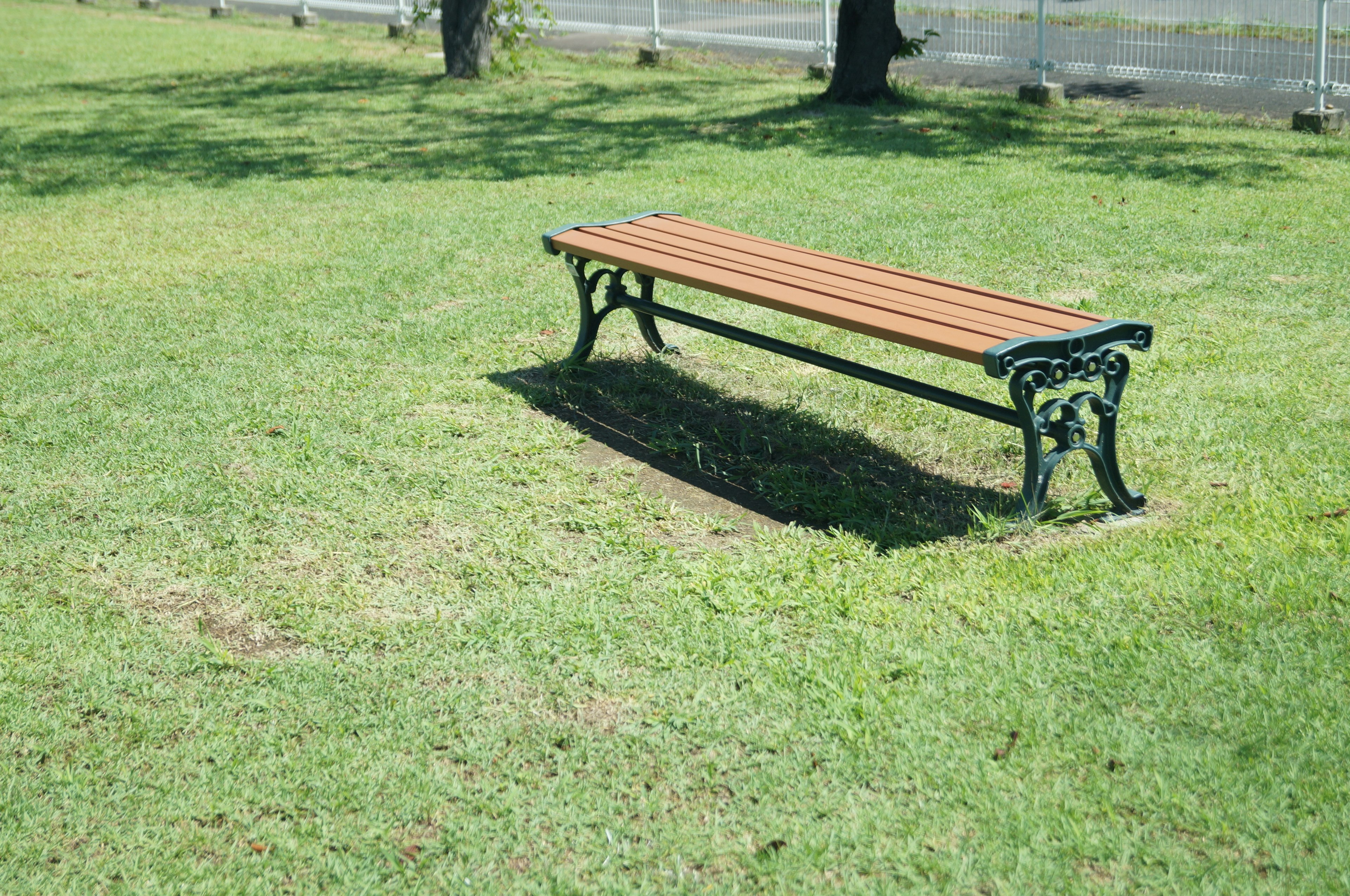 公園の芝生の上に置かれた木製のベンチ