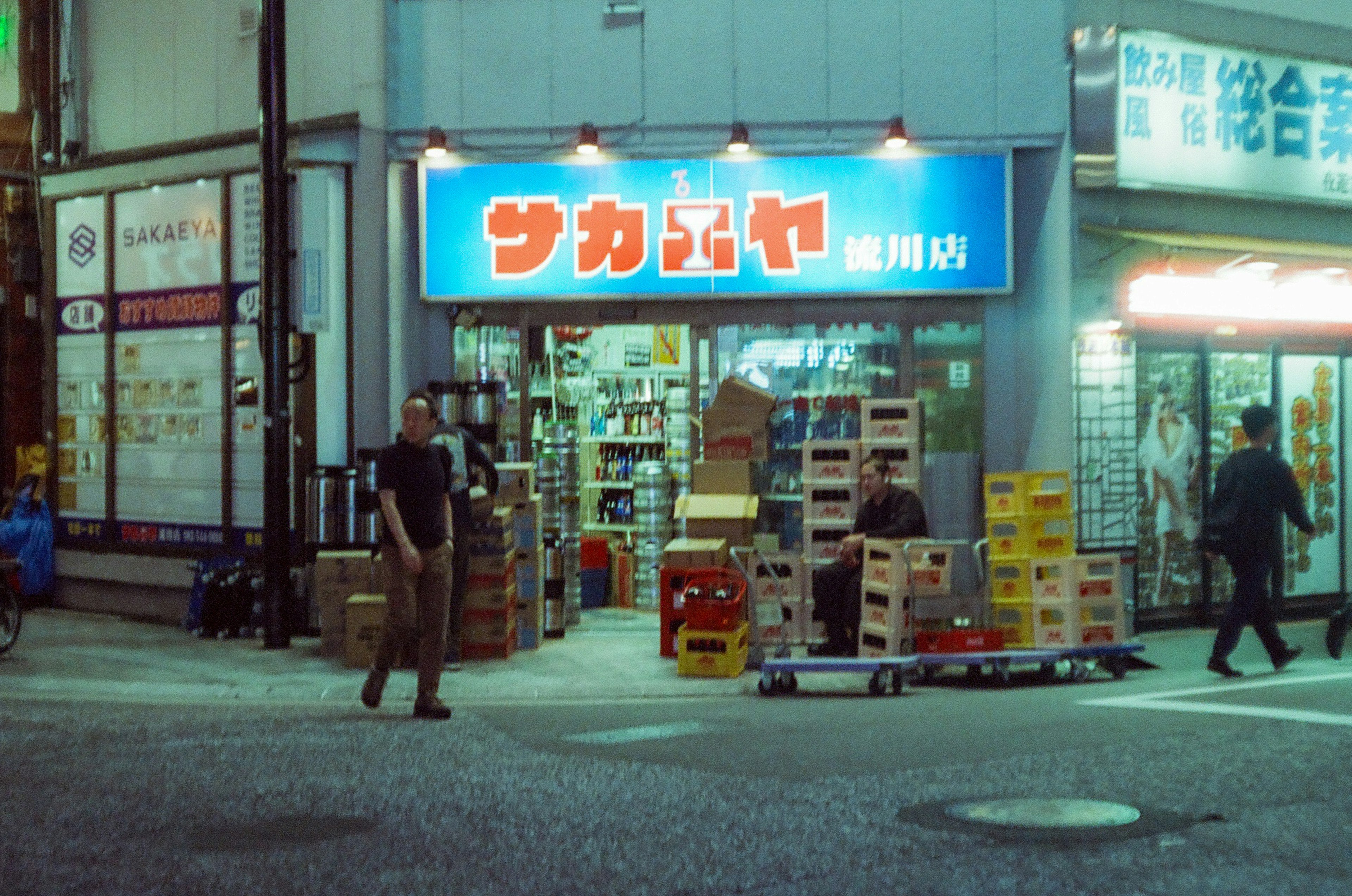 夜の街角にある小さな商店とその周辺の様子