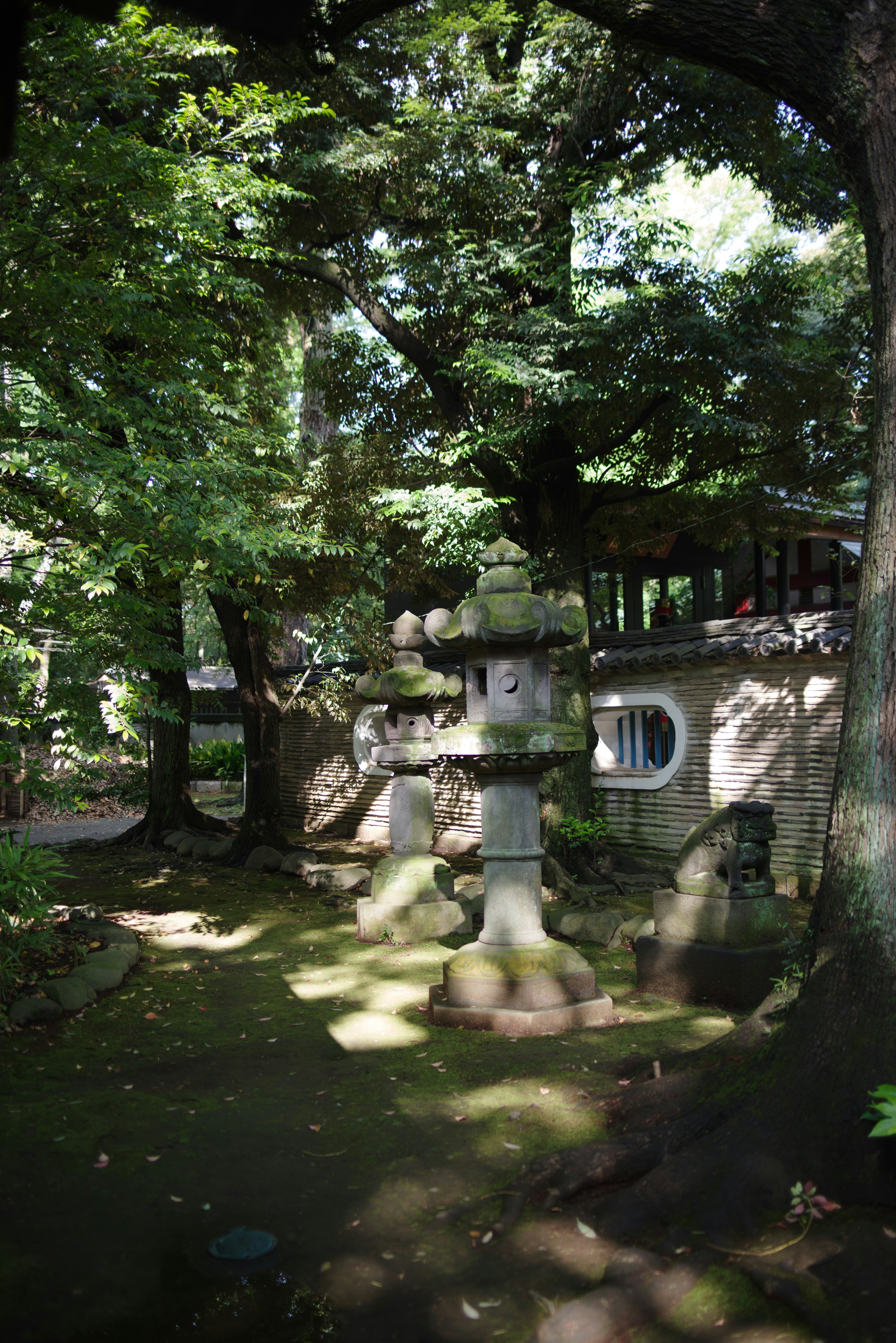 Japanese garden featuring a stone lantern surrounded by lush greenery and traditional architecture