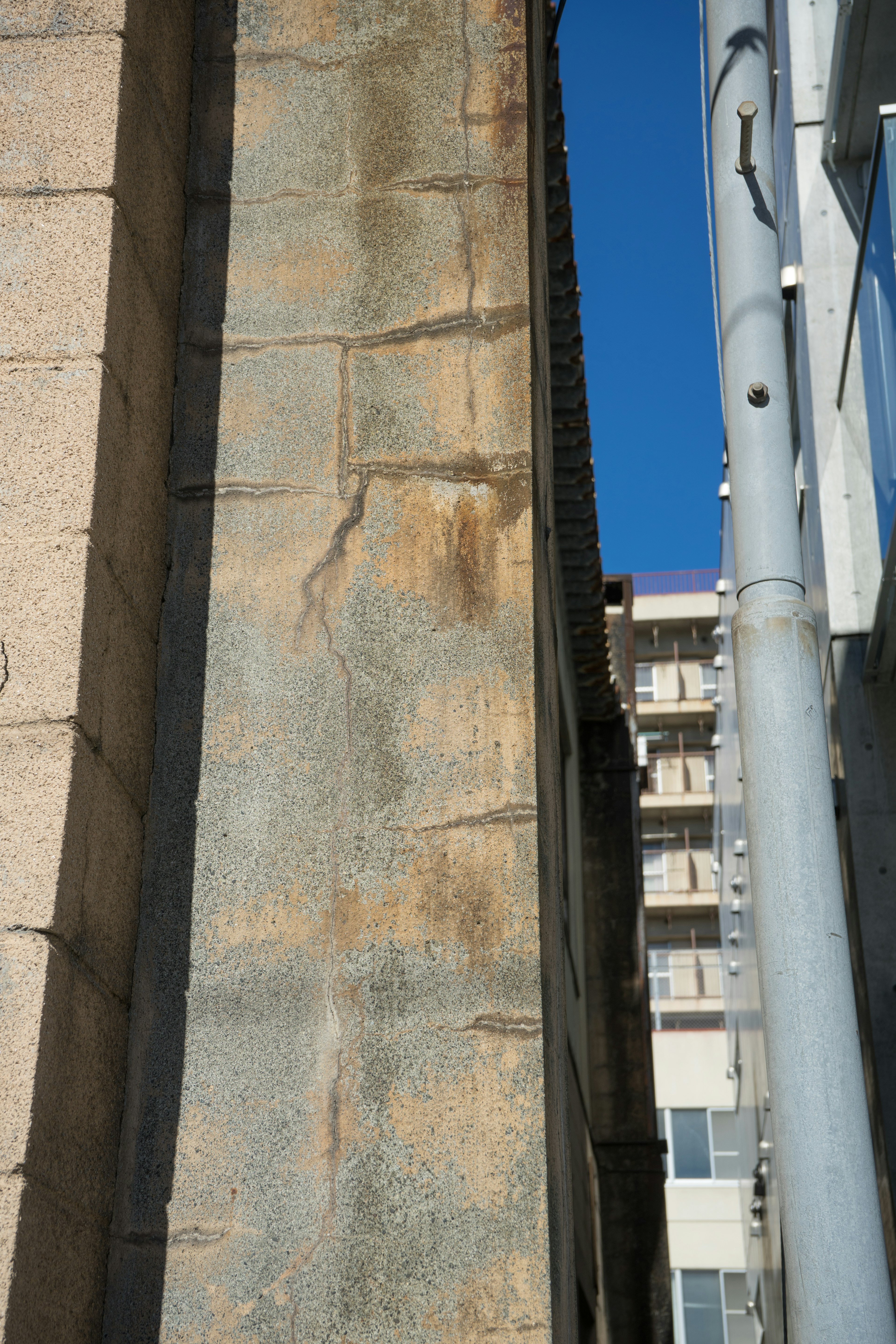 Primo piano di un muro di edificio sotto un cielo blu che mostra il contrasto tra pietra antica e struttura moderna