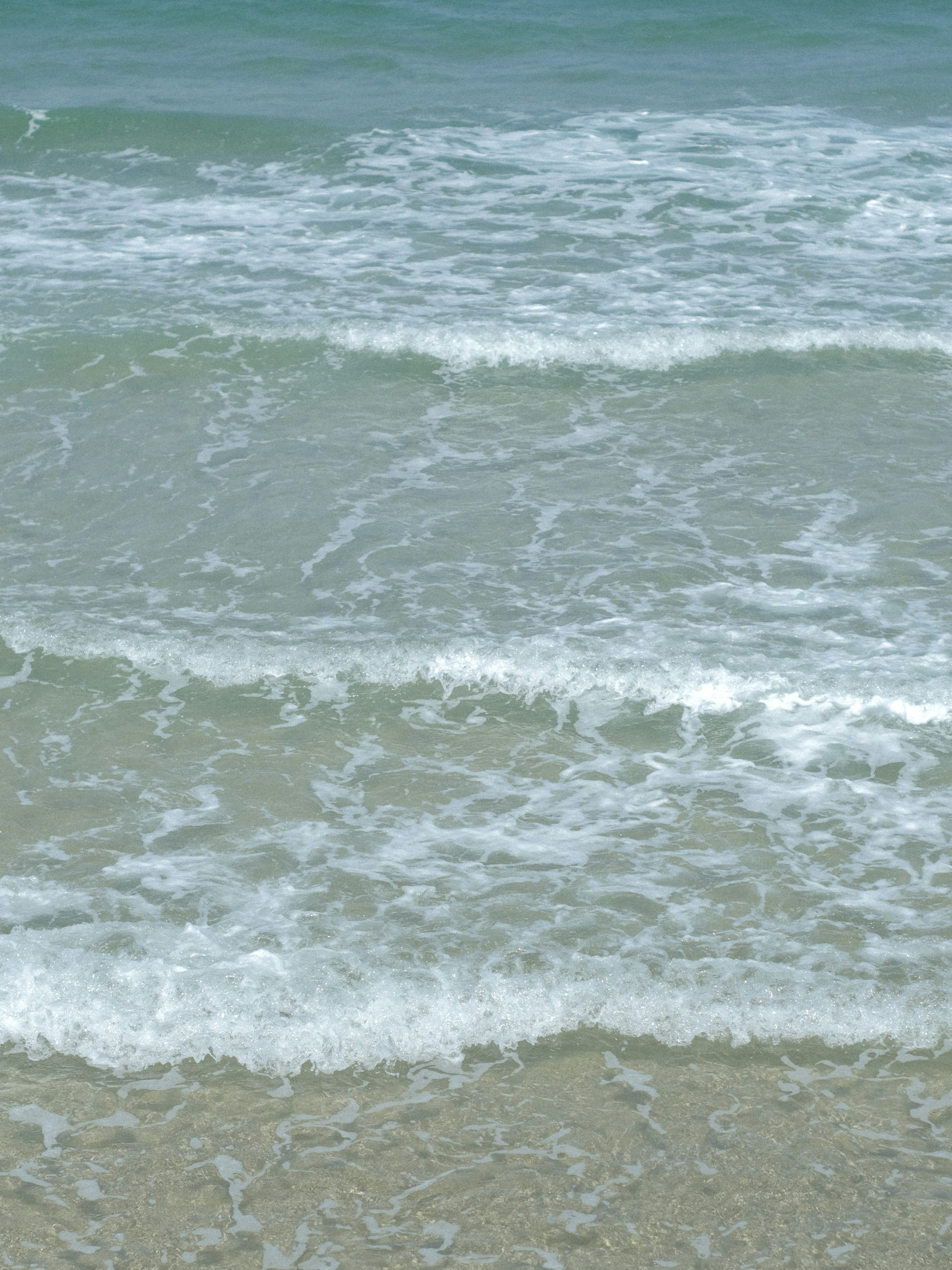 Sanfte Ozeanwellen, die an den Sandstrand schlagen