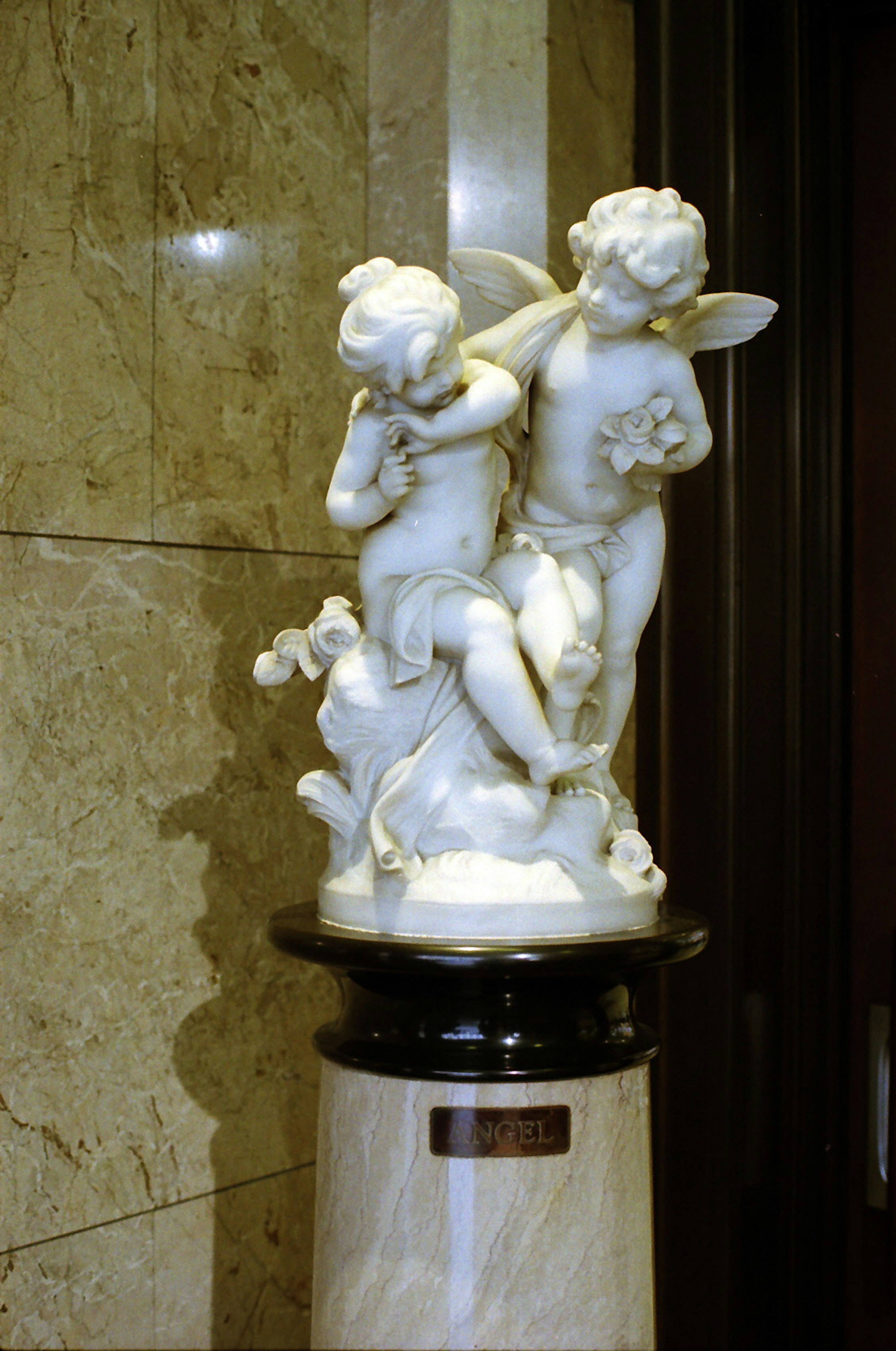 Scultura di angelo in marmo bianco con due bambini cherubini che giocano