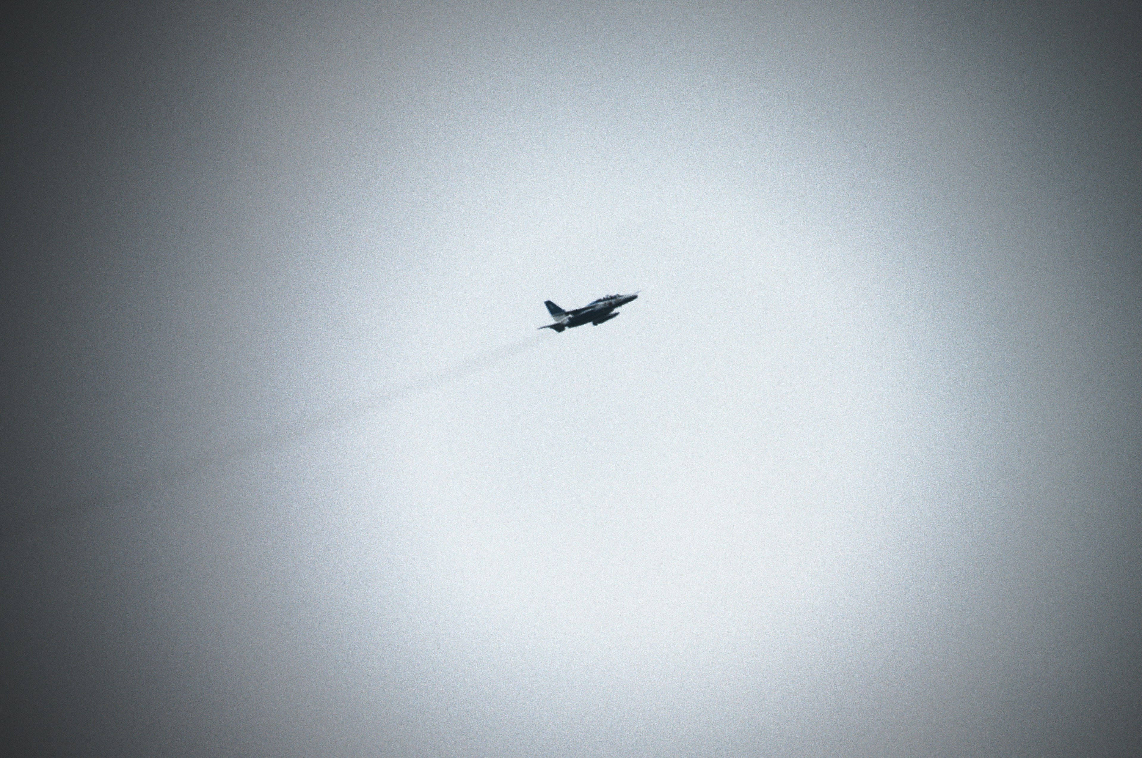 Silhouette of a jet flying with a smoke trail