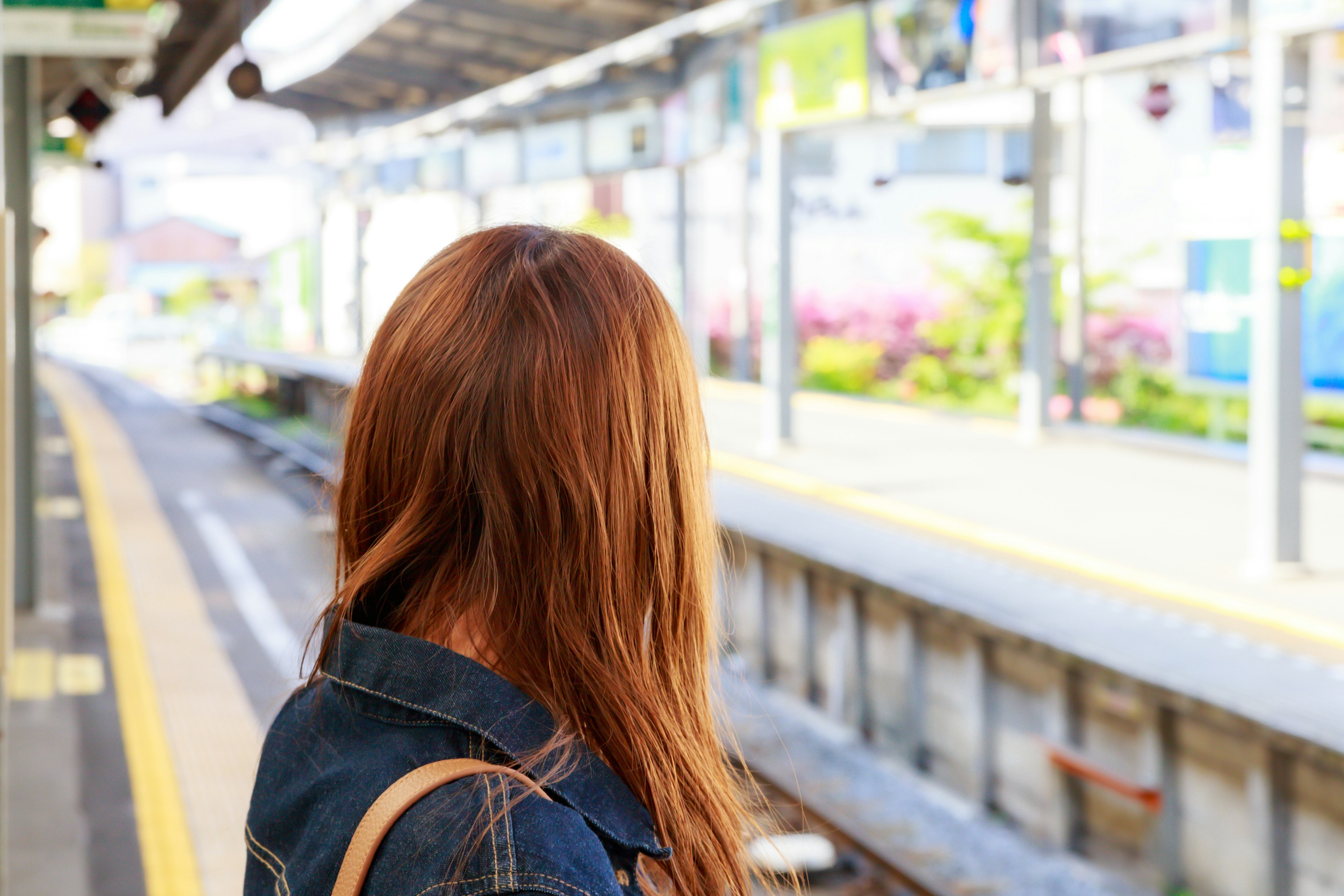 Frau wartet auf einen Zug an einem Bahnsteig