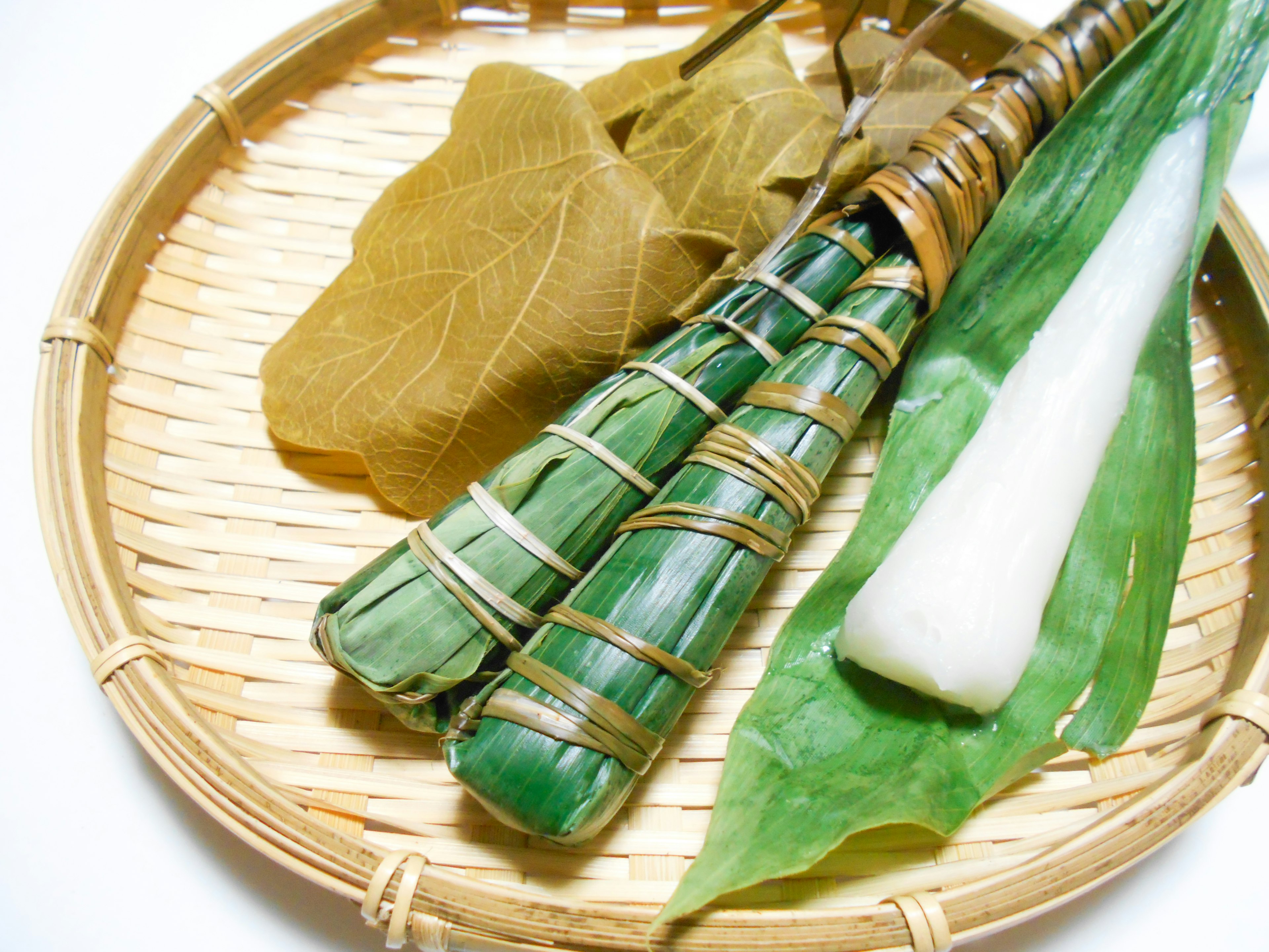 Traditional Japanese ingredients wrapped in bamboo leaves with a bamboo tray