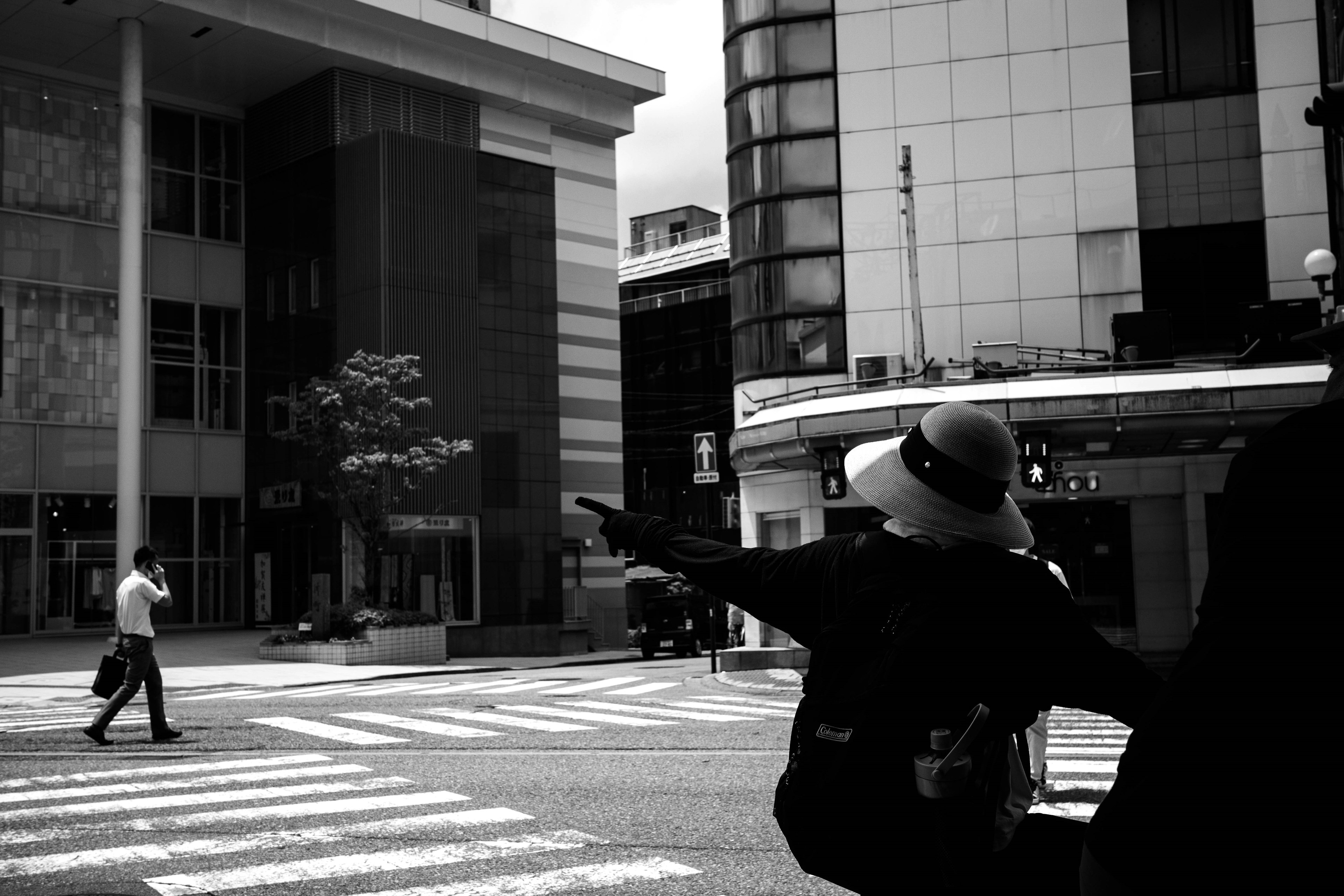 A black and white scene of people crossing at an intersection