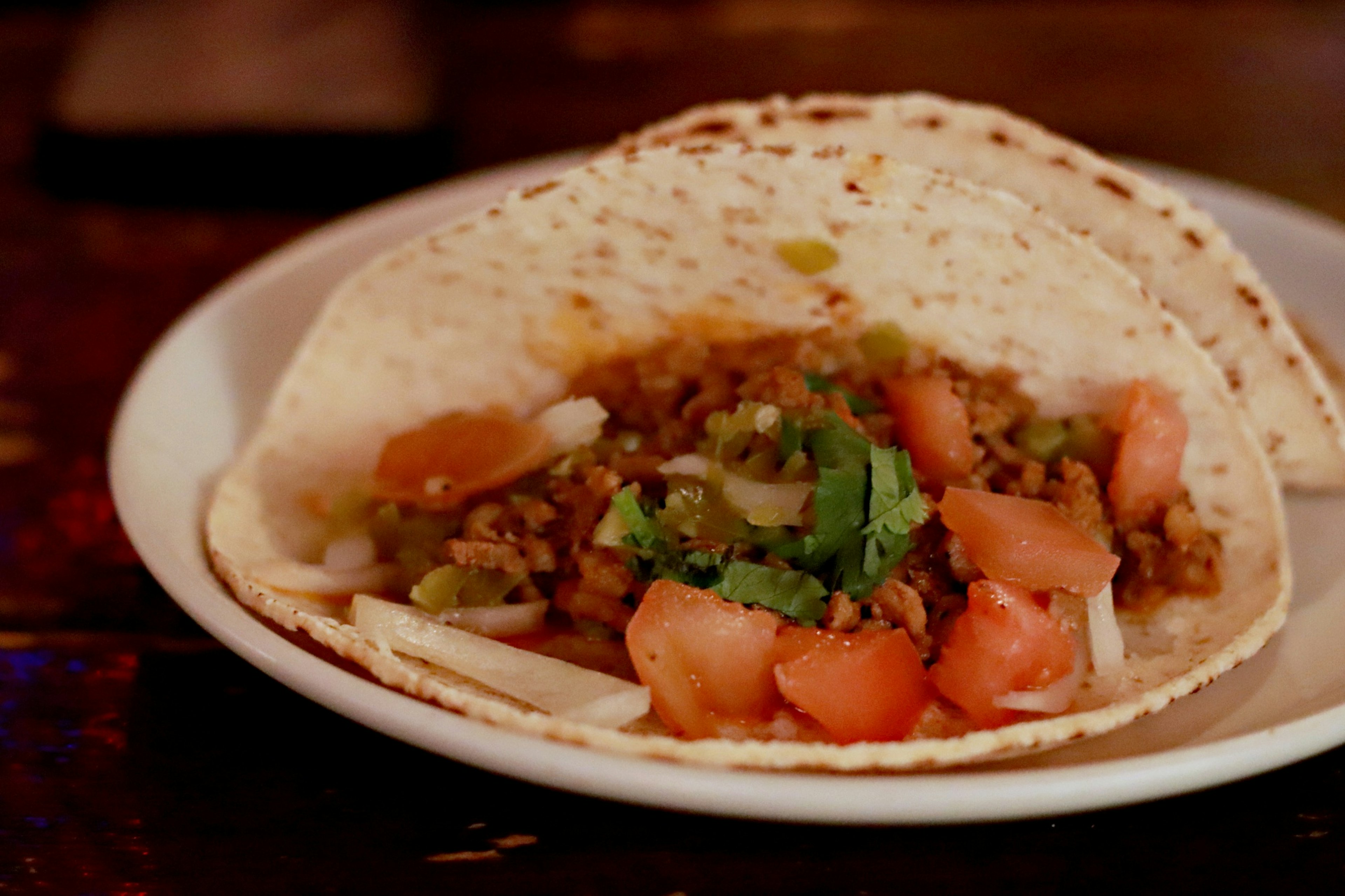 Delicious tacos served on a plate topped with tomatoes and herbs