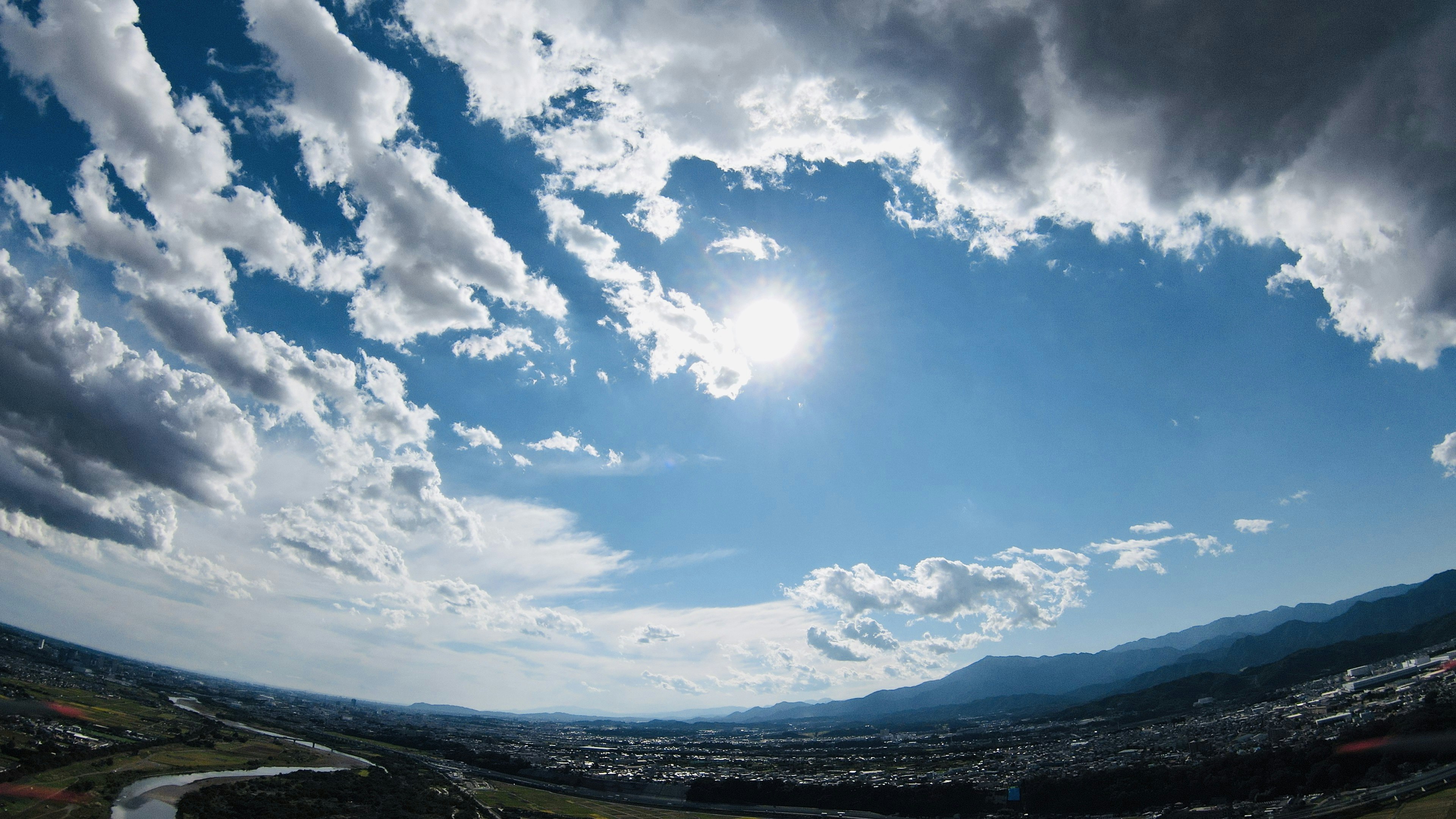 A scenic view of a blue sky with white clouds and the sun