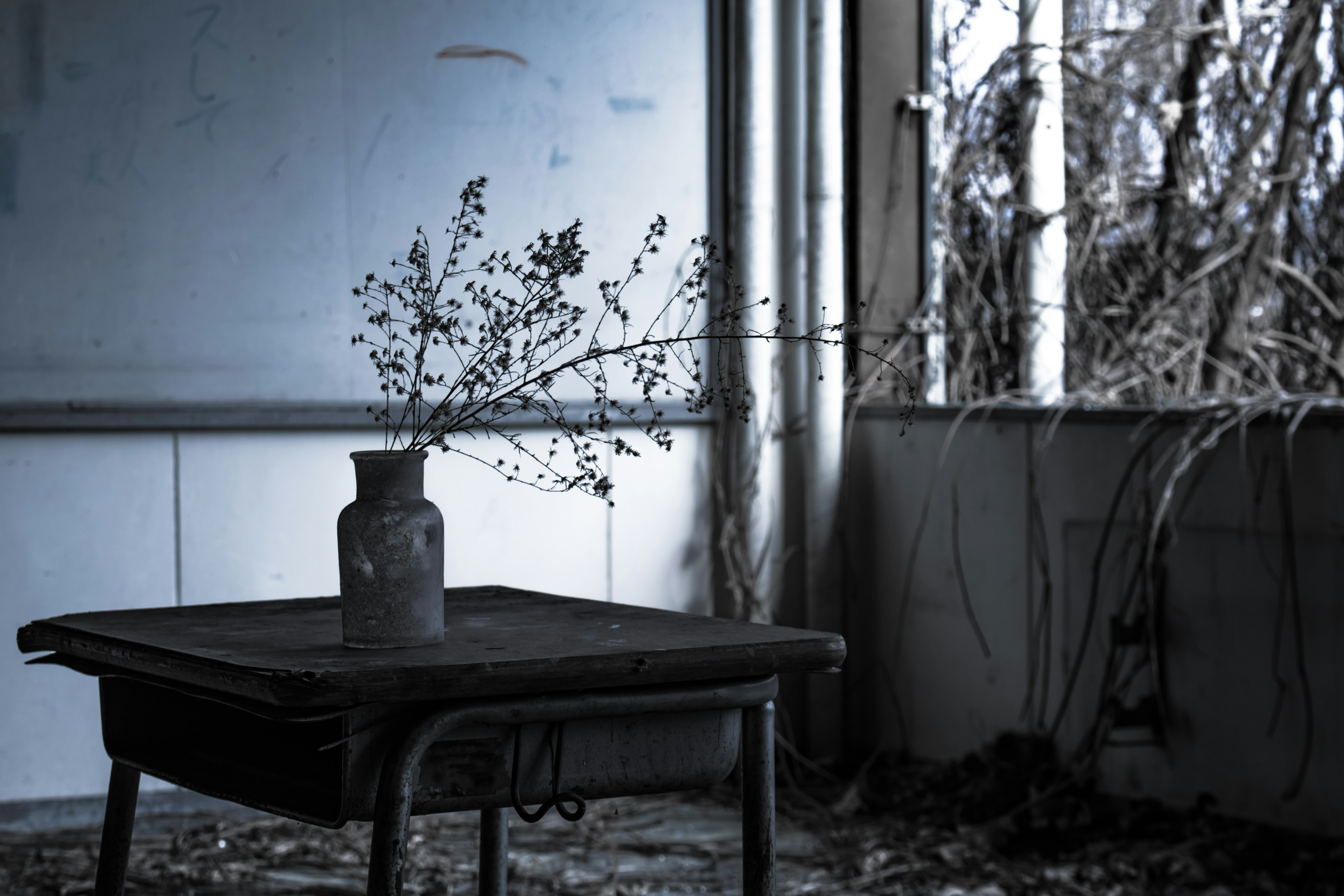 An abandoned room with a table and a vase containing dried plants