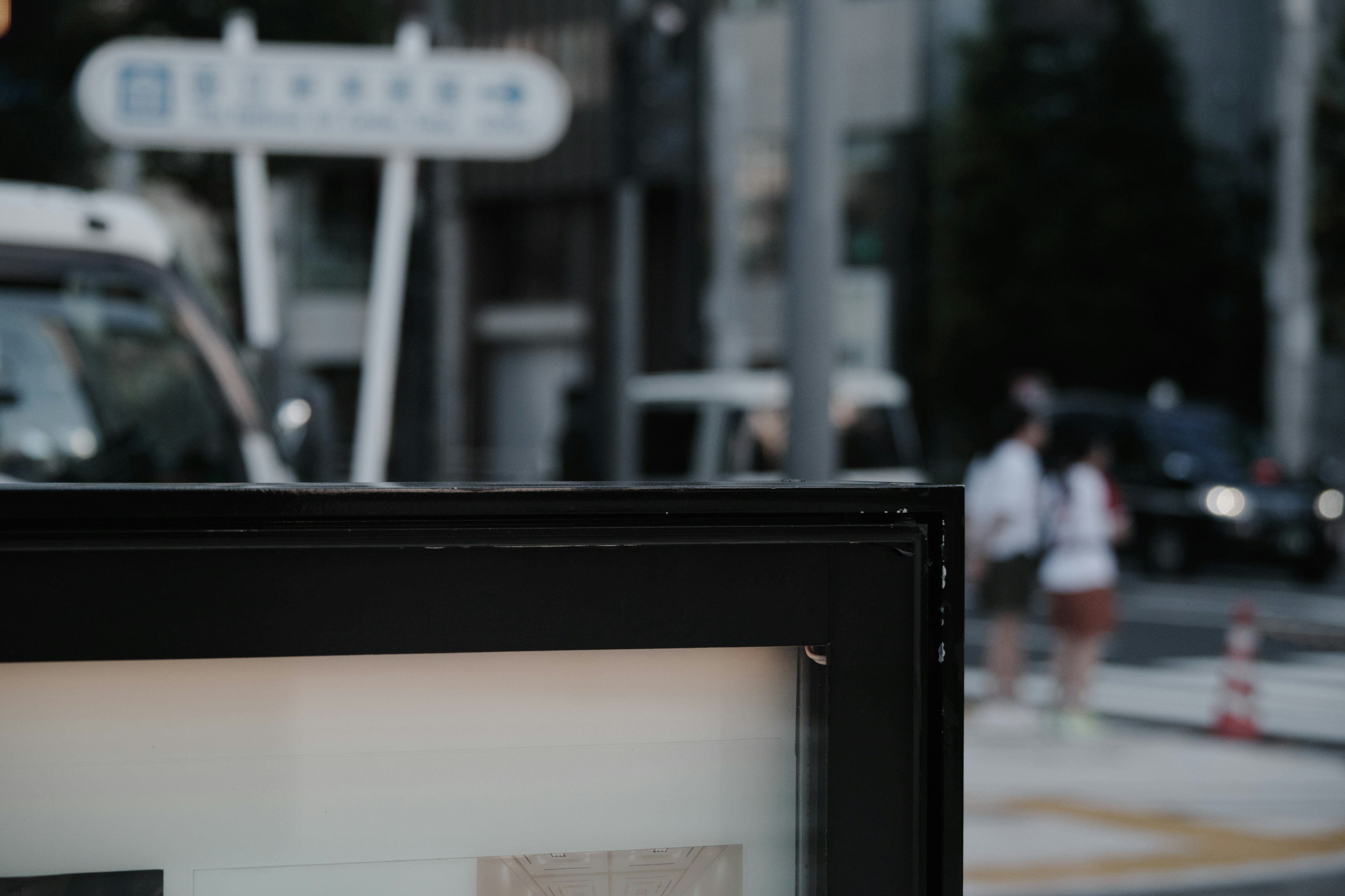 City bus stop with blurred vehicles and pedestrians in the background