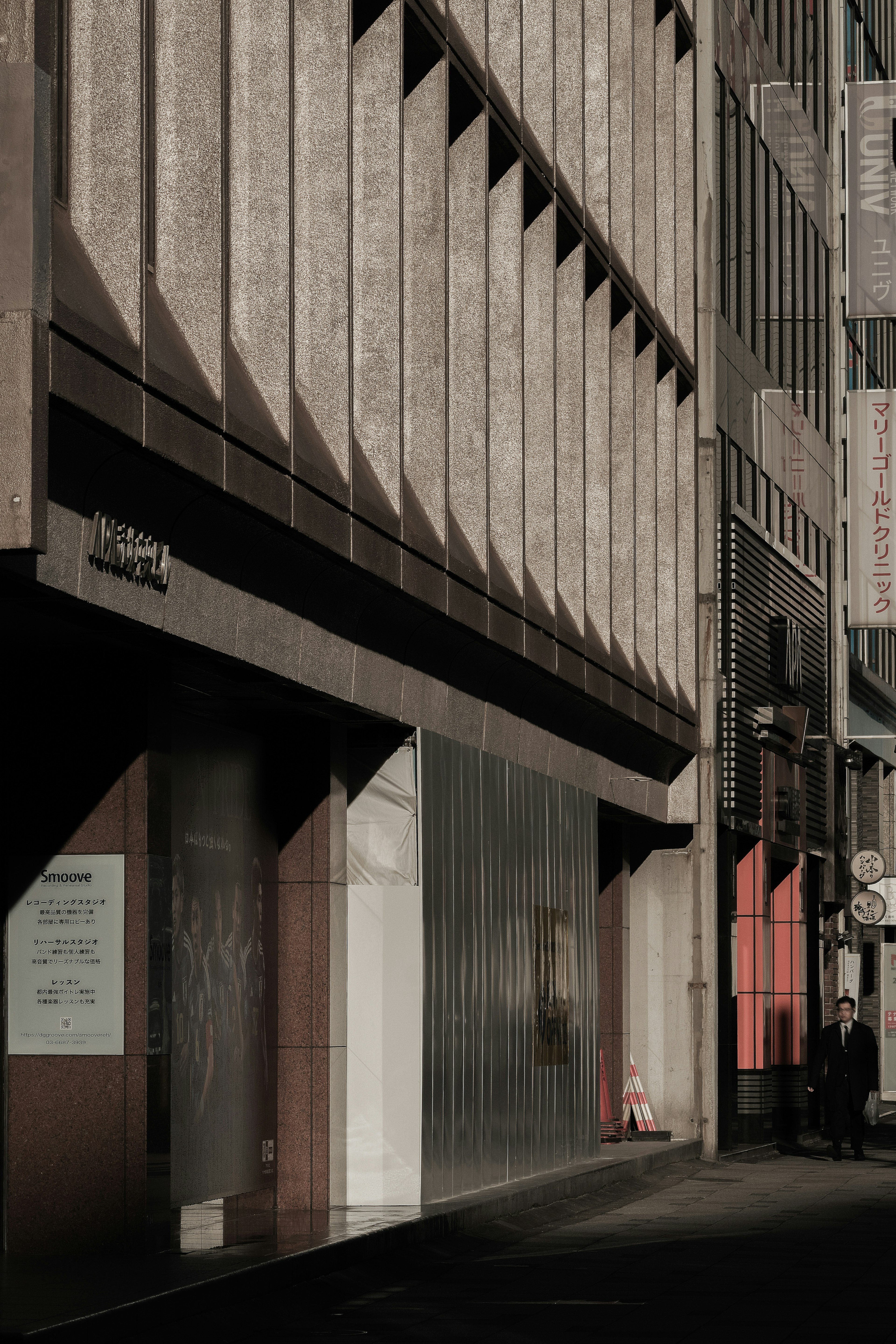 Façade d'un bâtiment moderne dans une rue urbaine sombre avec des ombres