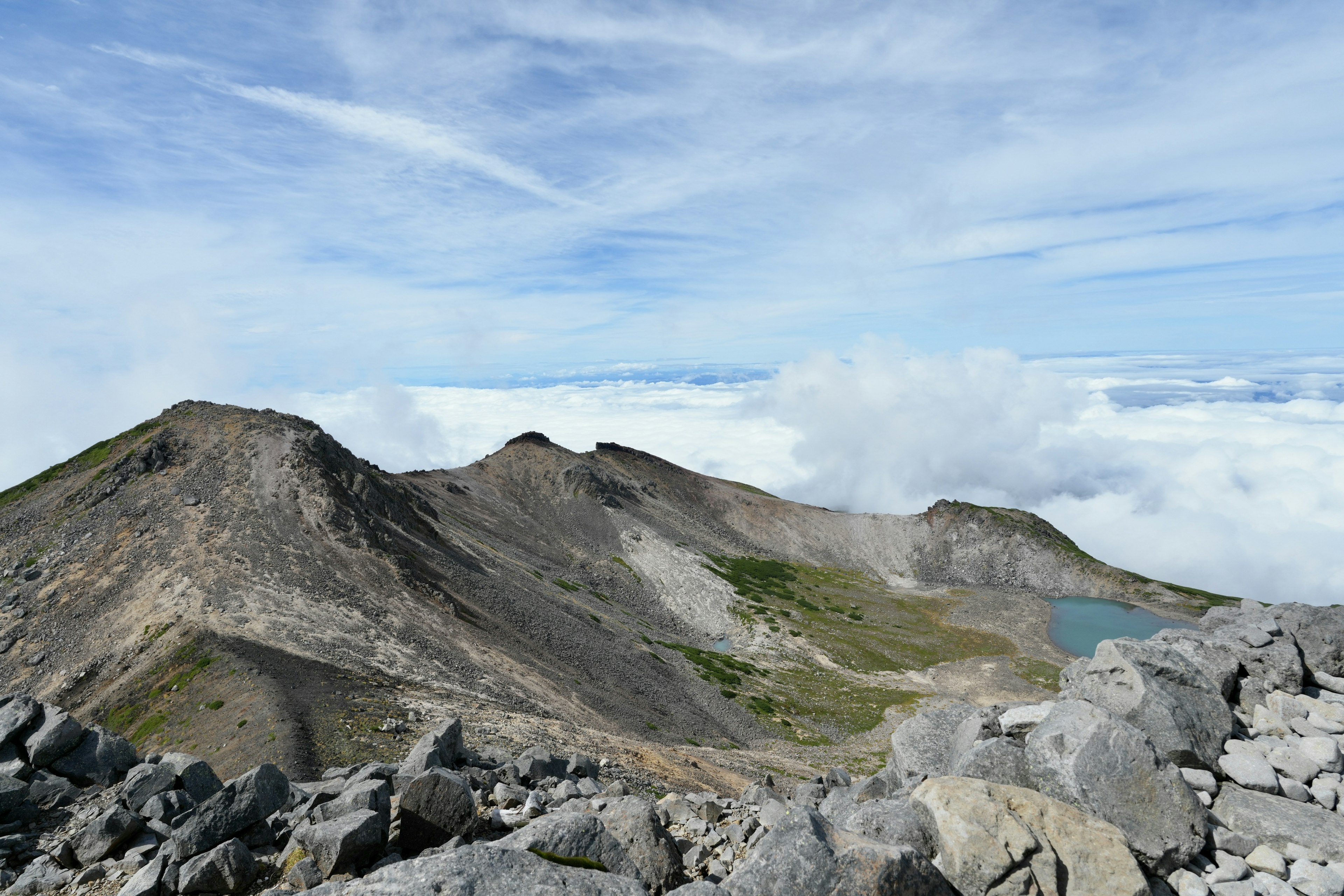 山の頂上から見た風景で青い空と雲が広がる山々が見える