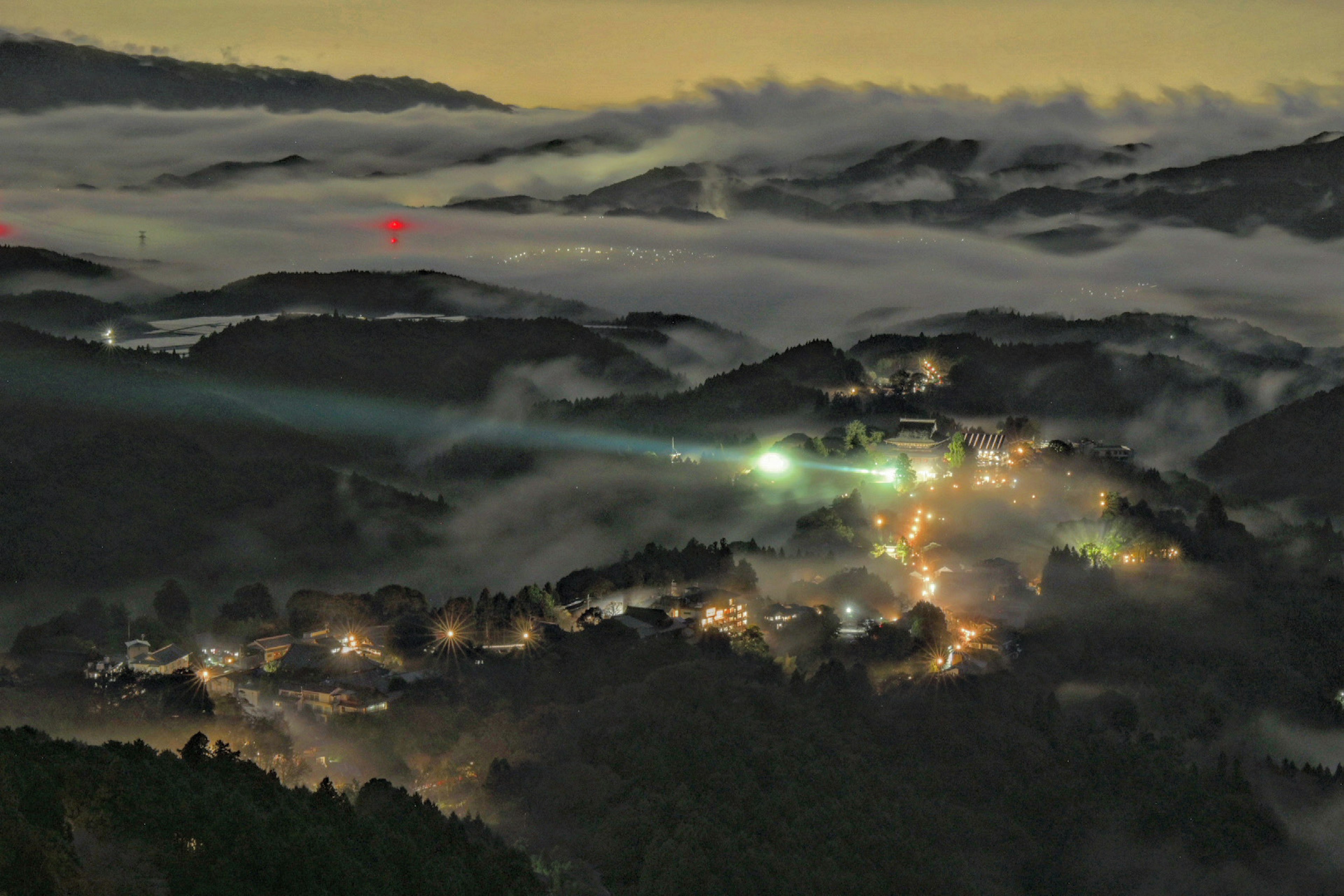 Night view of a misty mountain village with illuminated houses glowing softly