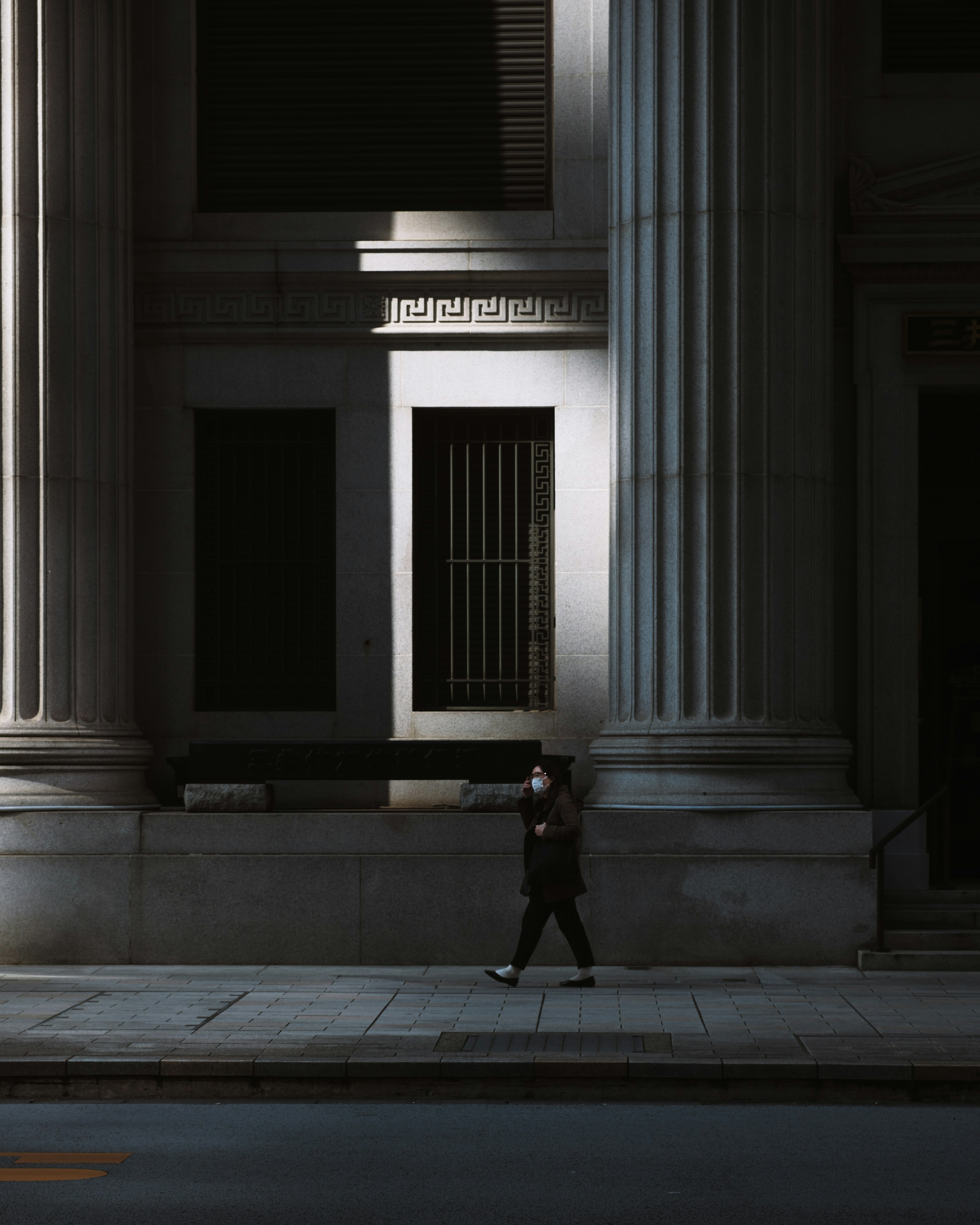 Une personne marchant dans l'ombre d'un bâtiment à colonnes