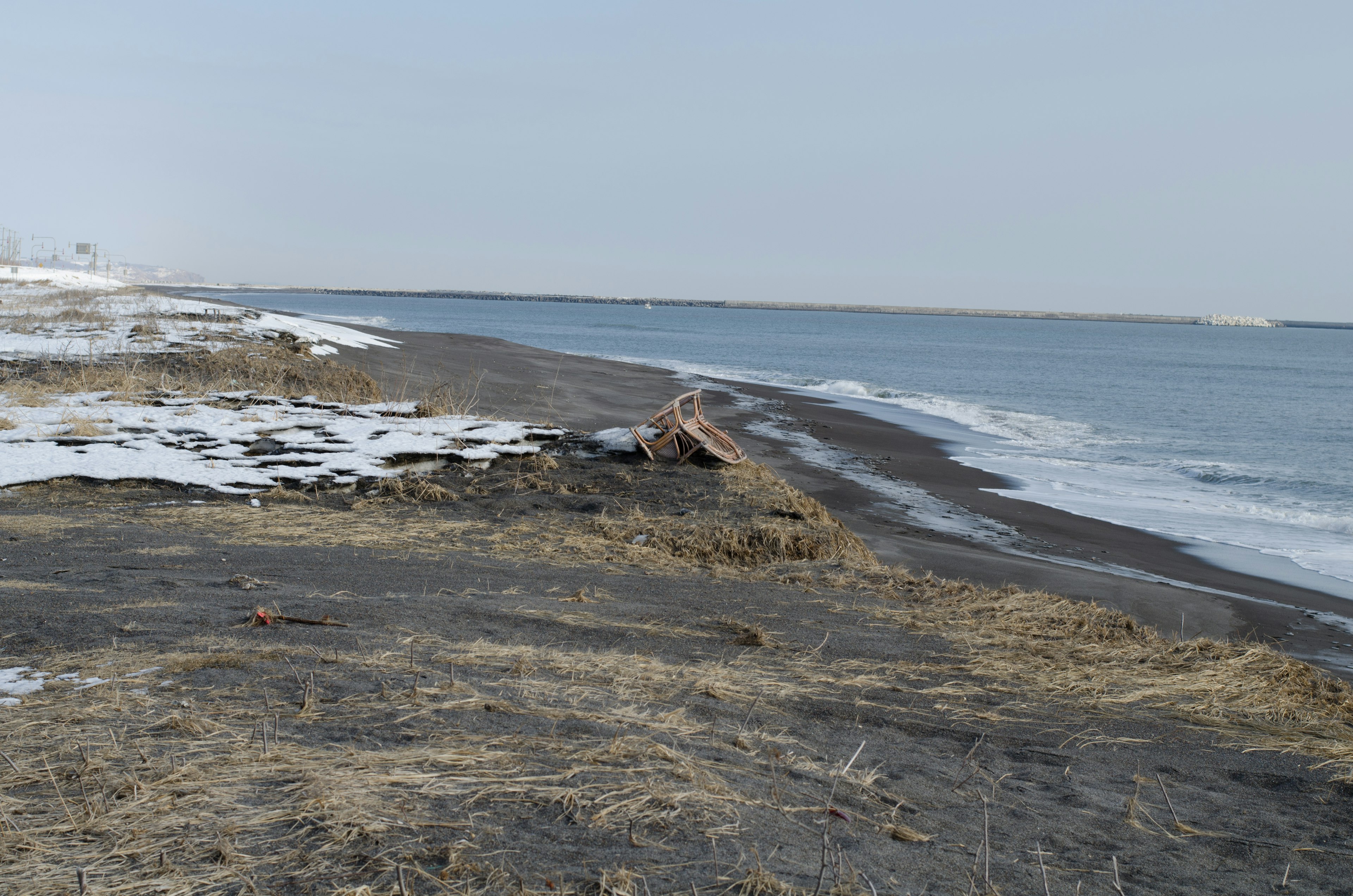 Winter coastline featuring a black sandy beach and remaining snow